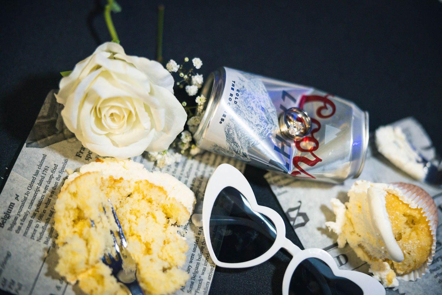 White roses and desserts arranged with vintage style decorations on dark background.