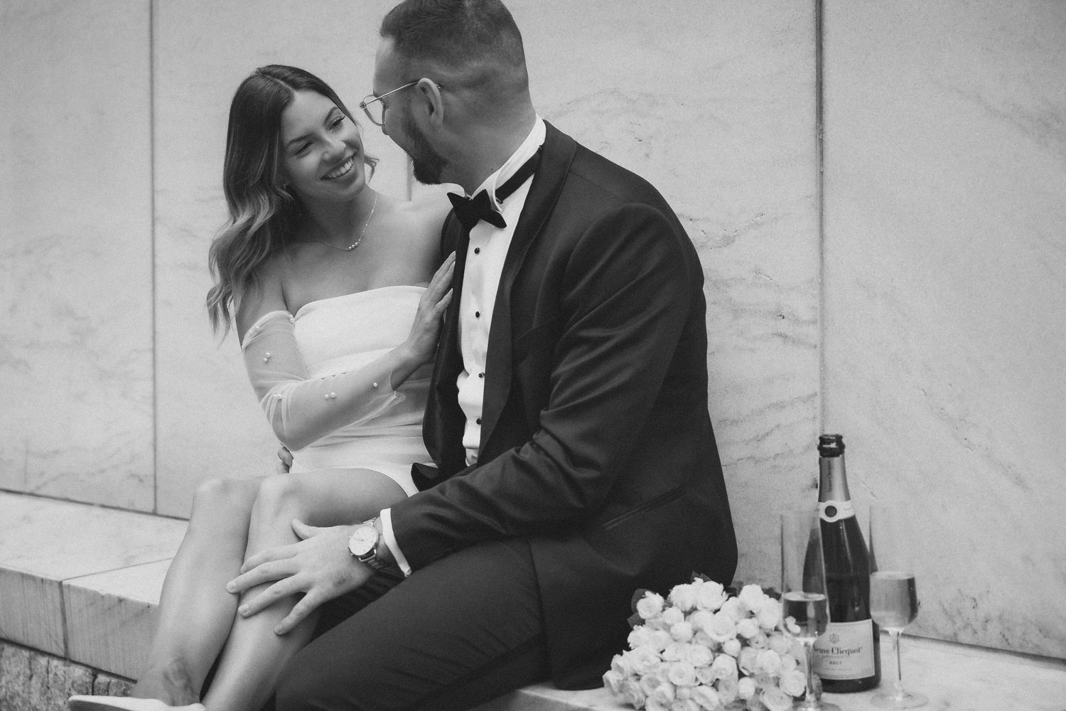 Black and white photography of intimate celebration moments with champagne and flowers.