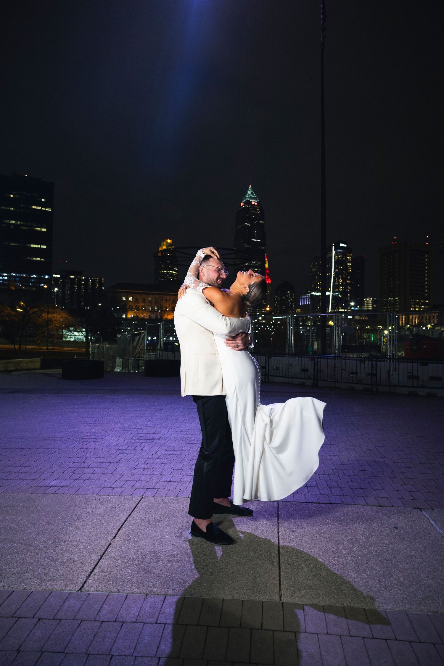 Dramatic nighttime dance pose with city lights creating a romantic silhouette.
