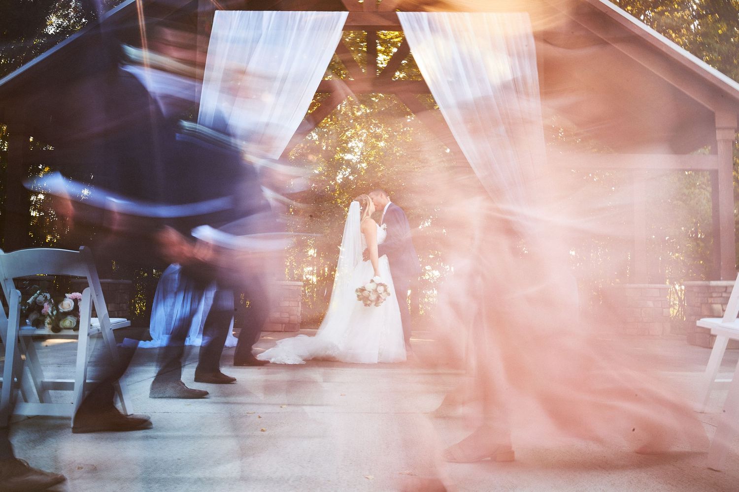 Abstract motion blur of wedding dancers creating ethereal light patterns in pink and blue tones.