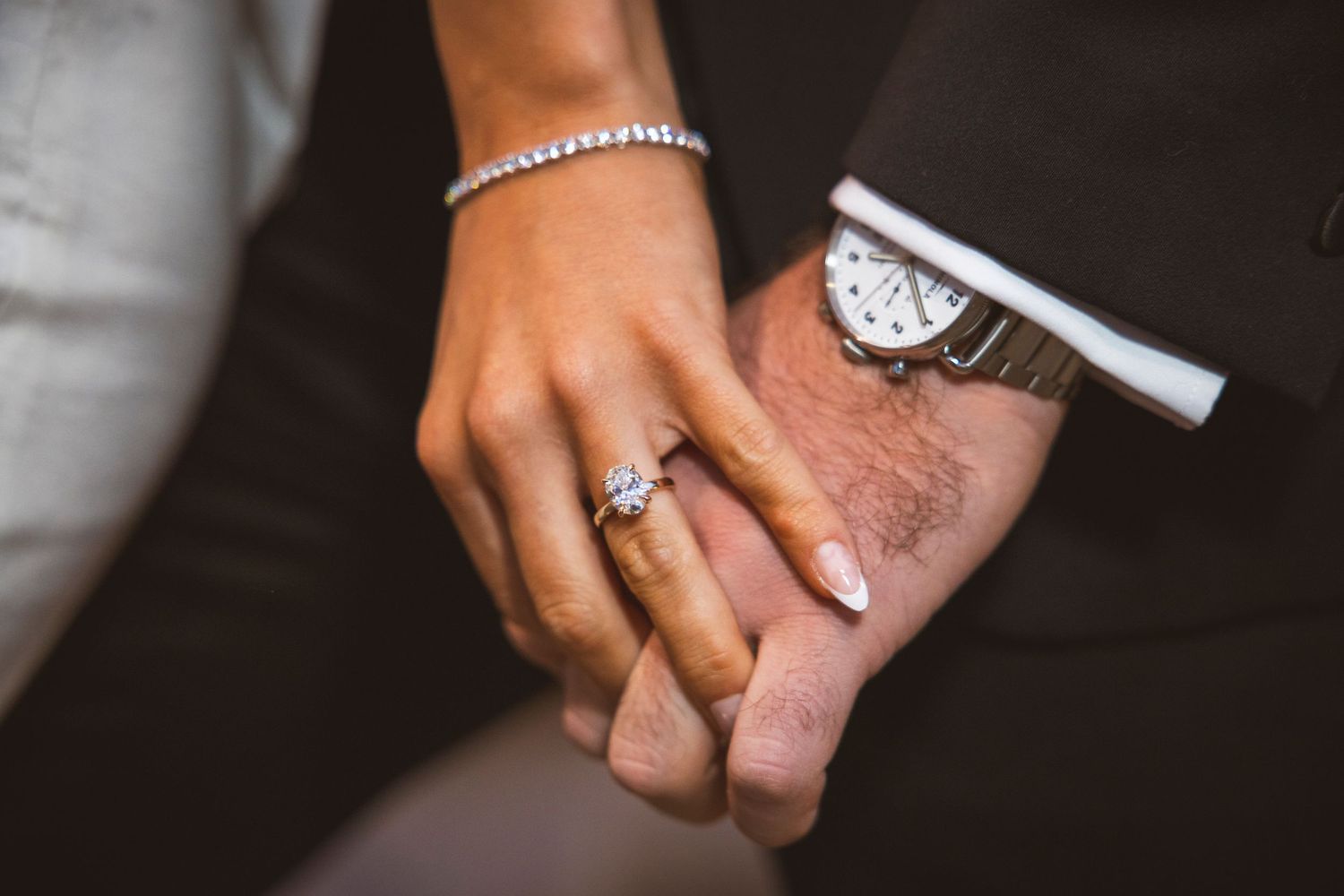 Detail shot of wedding rings and jewelry on hands during celebration.