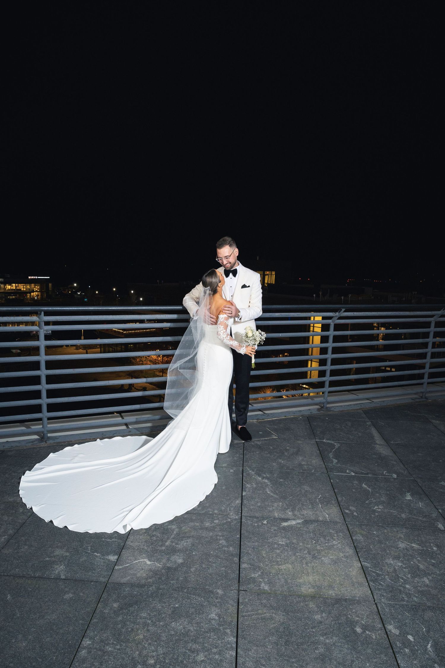 Couple shares romantic dance moment on outdoor terrace with flowing white wedding dress.