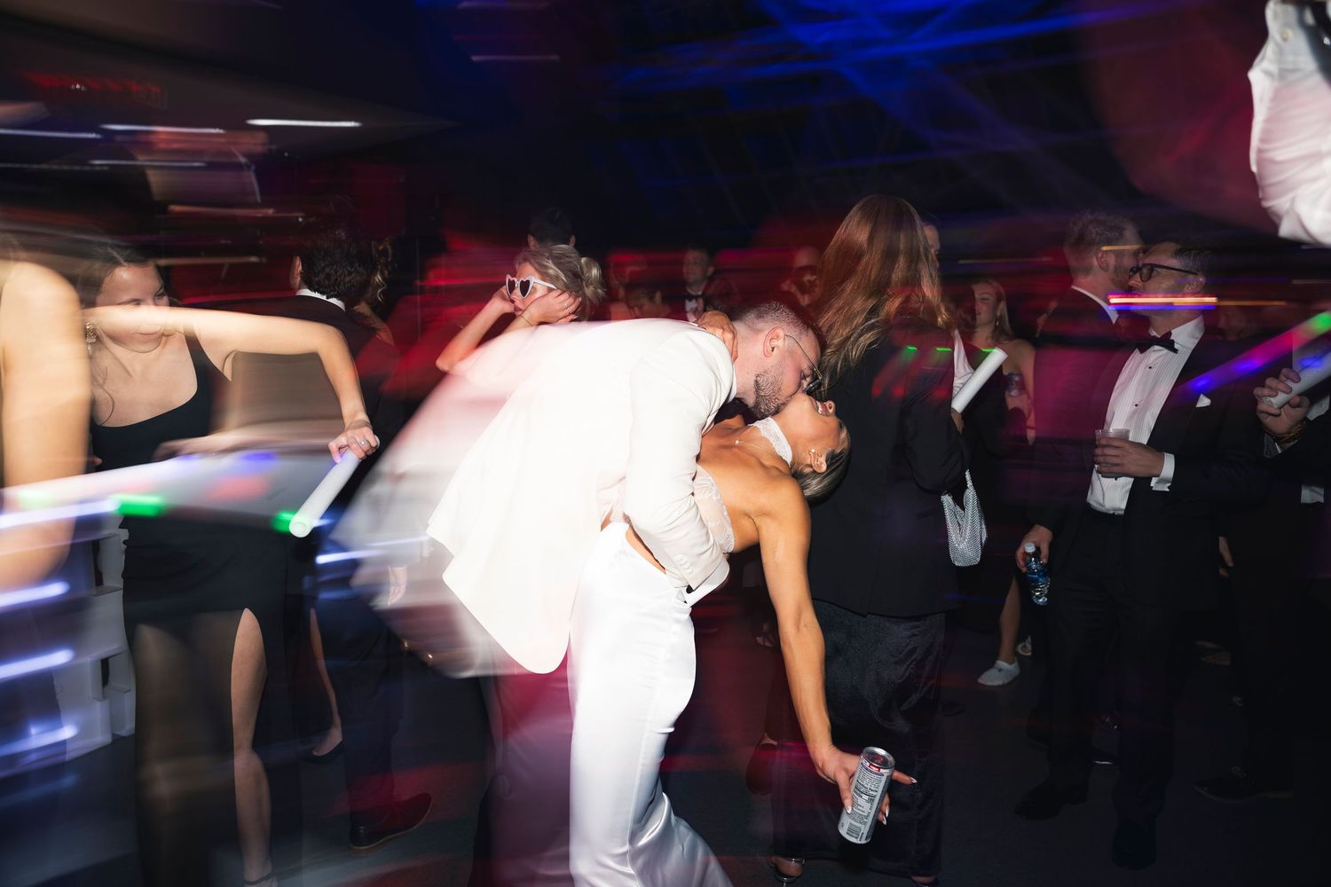 Dancing couples create silhouettes on a dark dance floor illuminated by blue and purple lighting.