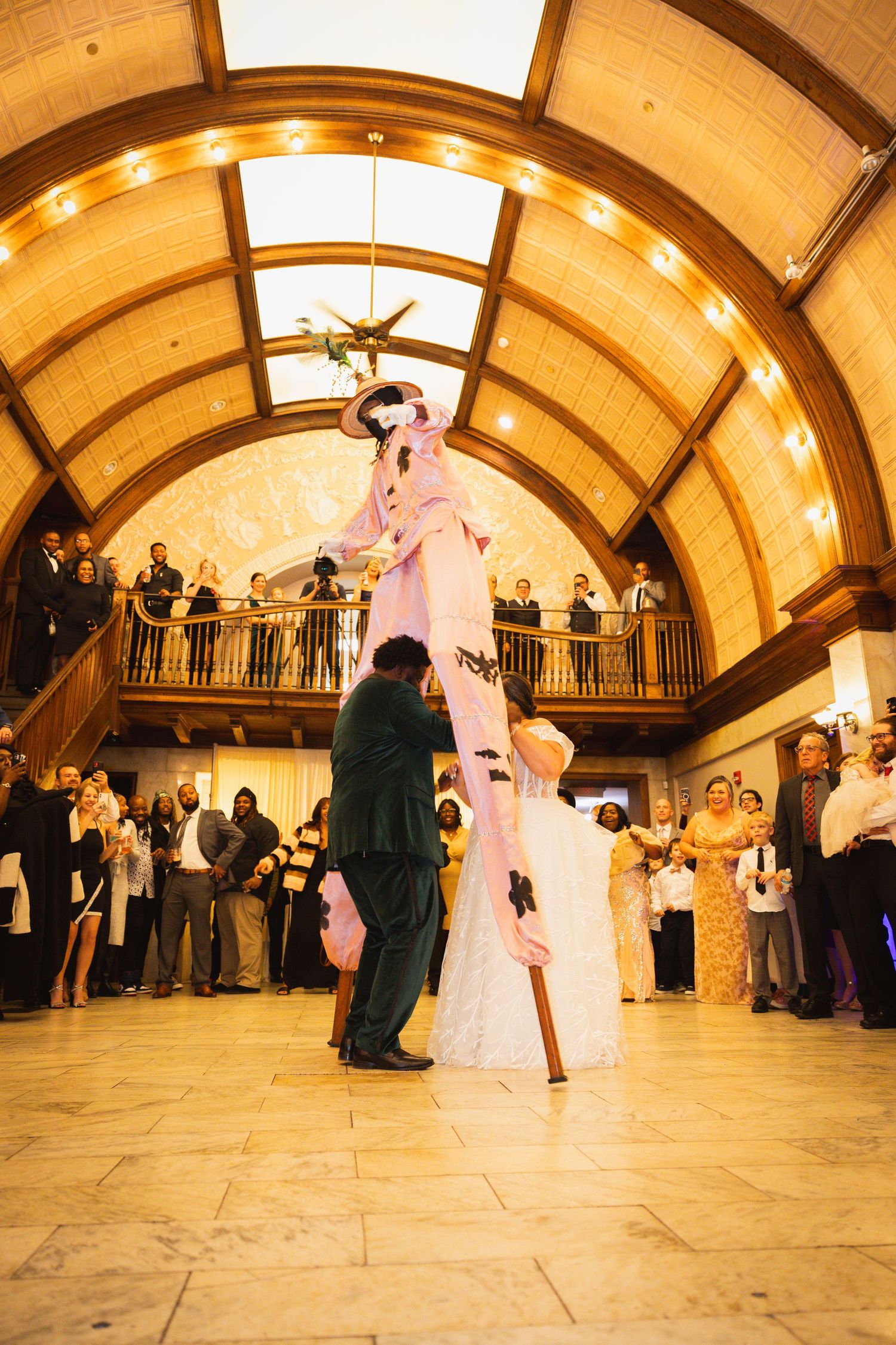 Couples dancing at a wedding reception in a beautiful arched ballroom with mood lighting.
