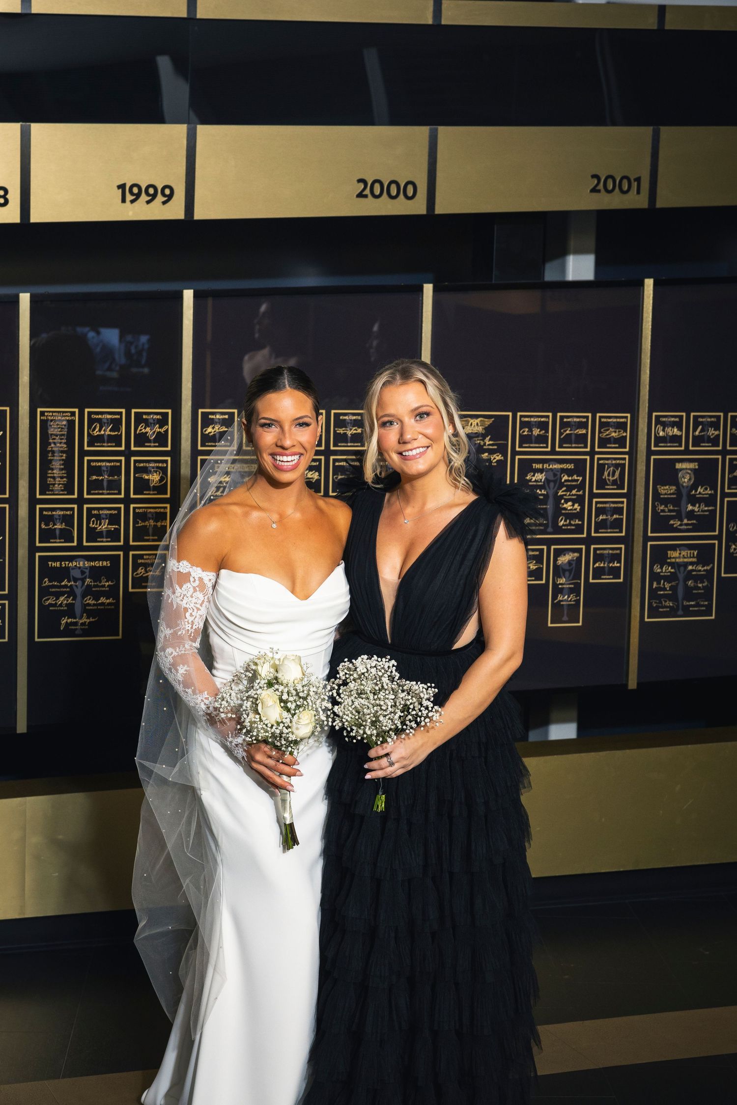 Wedding party members stand together wearing elegant black and white attire.