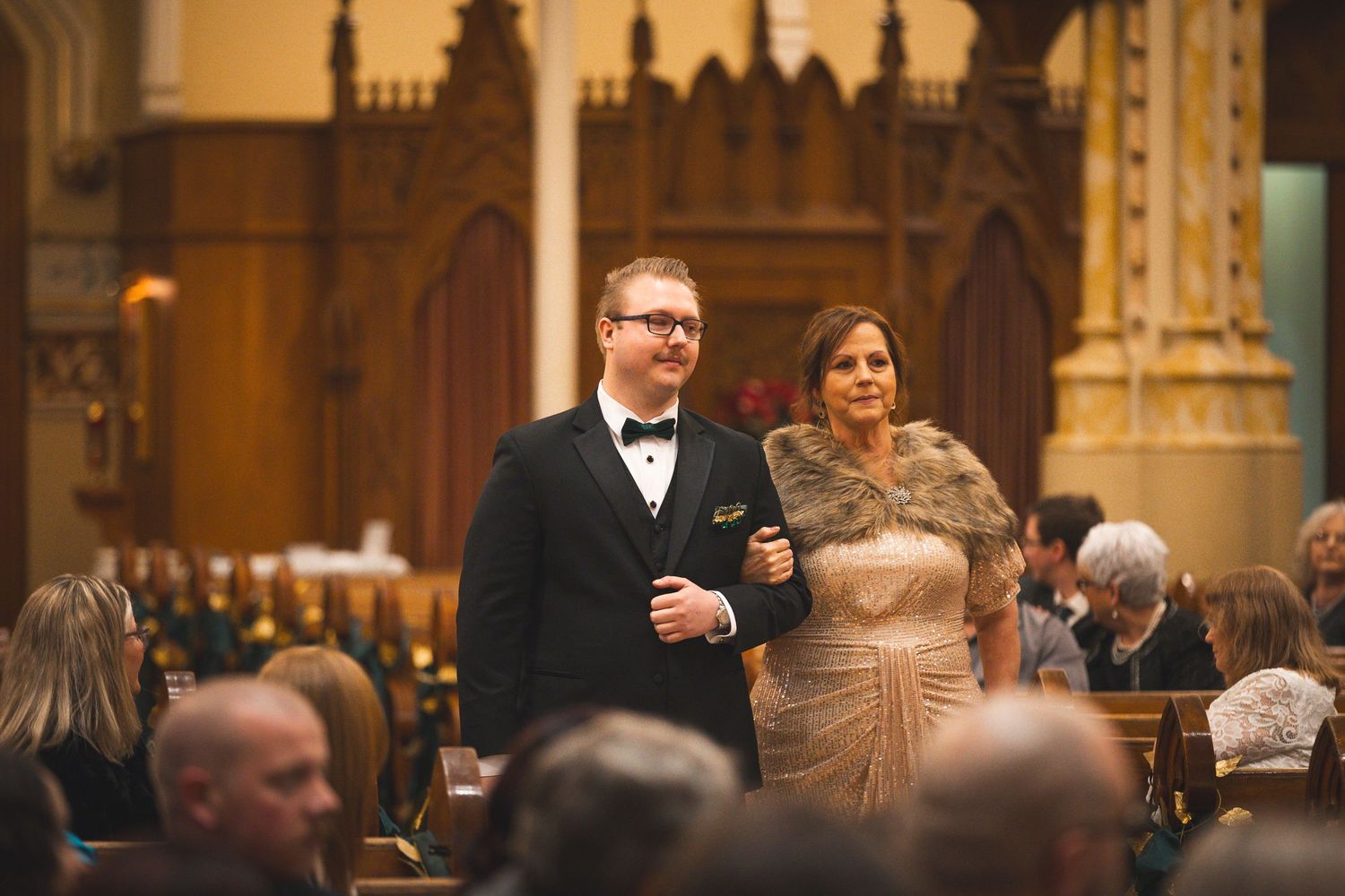 Wedding reception guests seated at elegantly decorated tables in a grand hall with ornate architectural details.