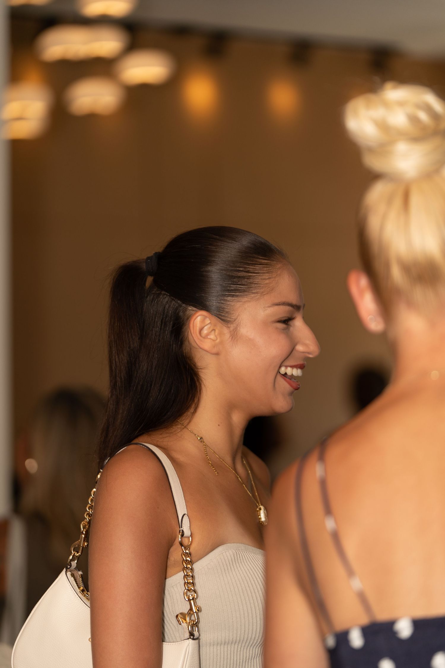 Two people sharing a joyful conversation in an indoor setting with warm lighting.