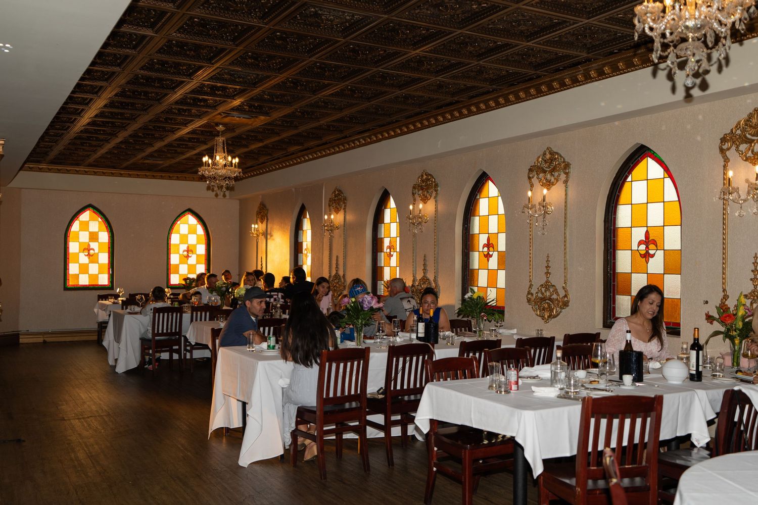 Elegant banquet hall with stained glass windows, crystal chandeliers, and formal table settings.