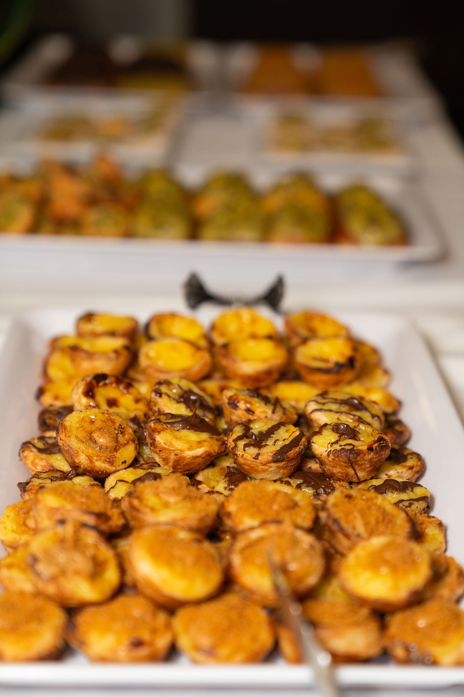 Golden pastries arranged in neat rows on white serving platters.