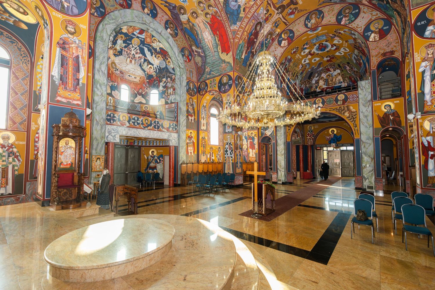 Panoramic view of an ornate Orthodox church interior with colorful frescoes, golden icons, and decorative arches.