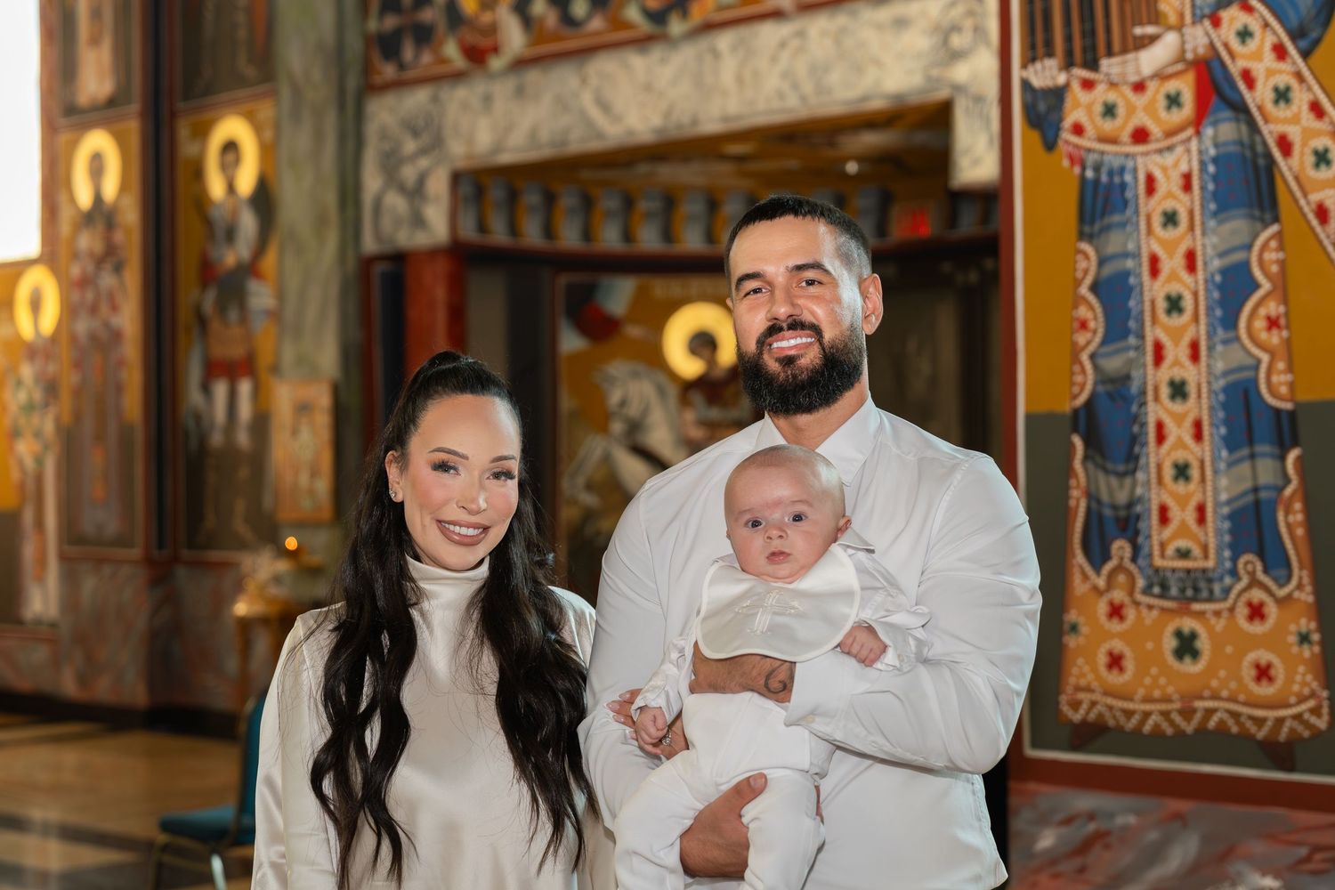 Orthodox Christian baptism ceremony in a traditional church with ornate Byzantine style religious icons and decorations.