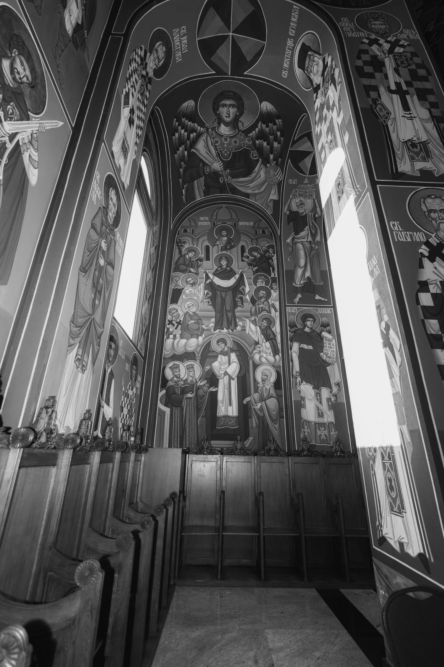 Black and white photograph of ornate religious murals and frescoes adorning the walls and ceiling of a church interior.
