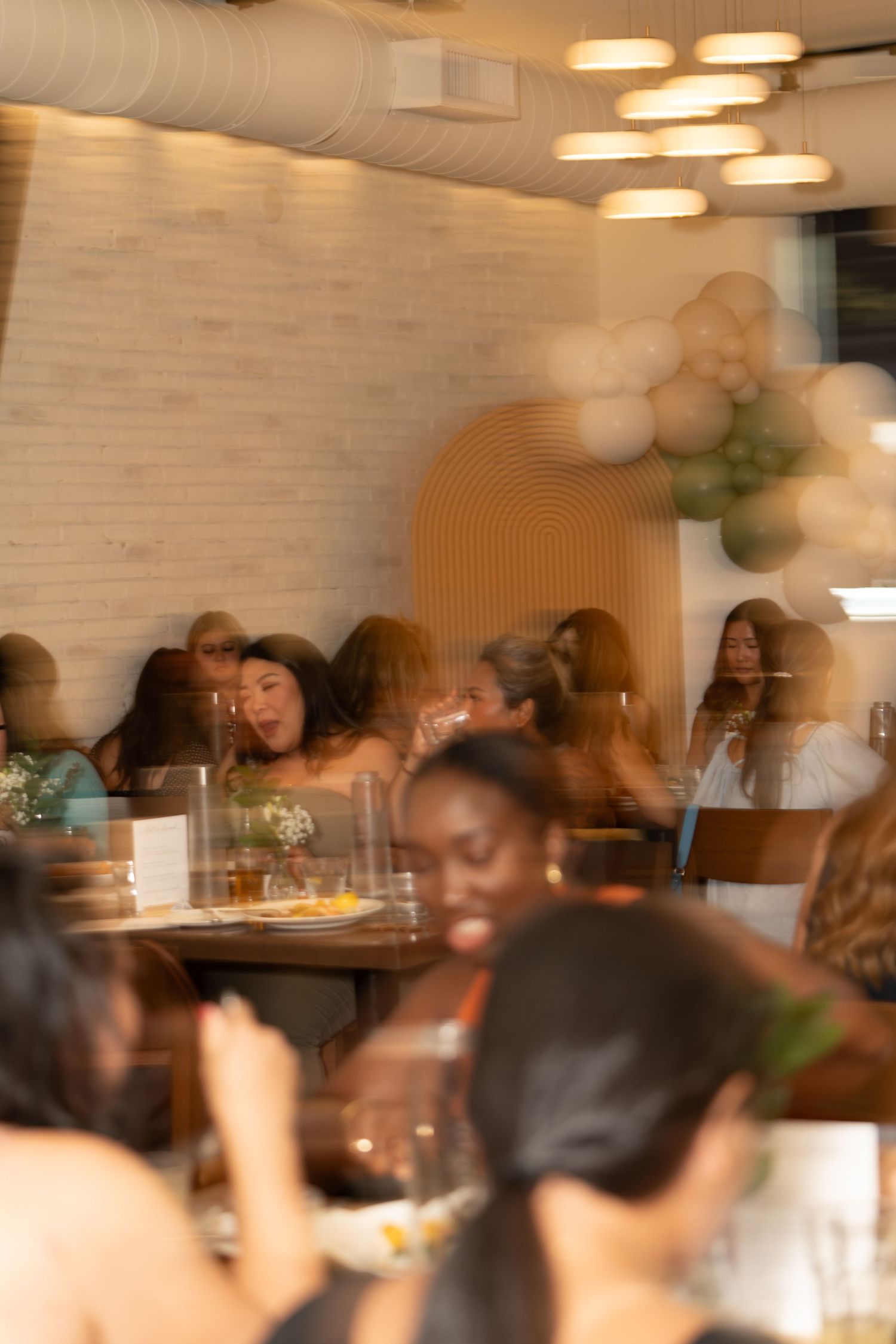 Blurred motion shot of diners enjoying a social gathering in a warmly lit restaurant.