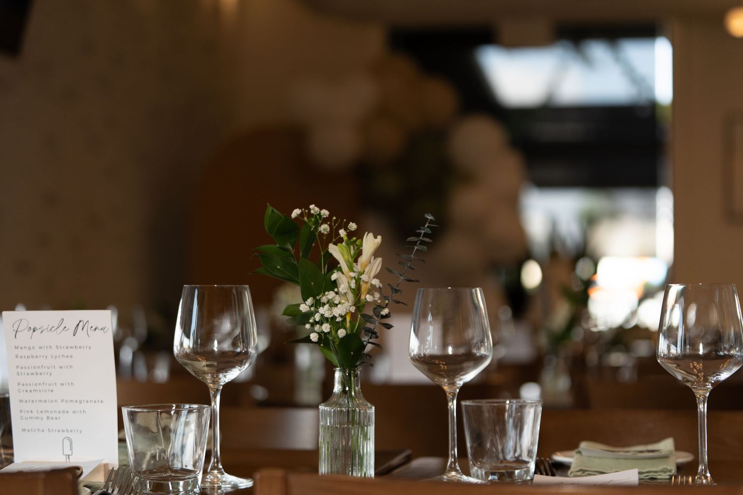 Elegant restaurant table setting with wine glasses and small floral centerpiece.