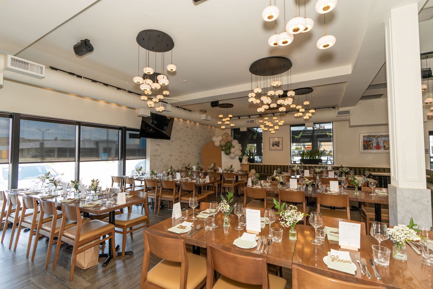 Modern restaurant interior with wooden tables and decorative pendant lighting.