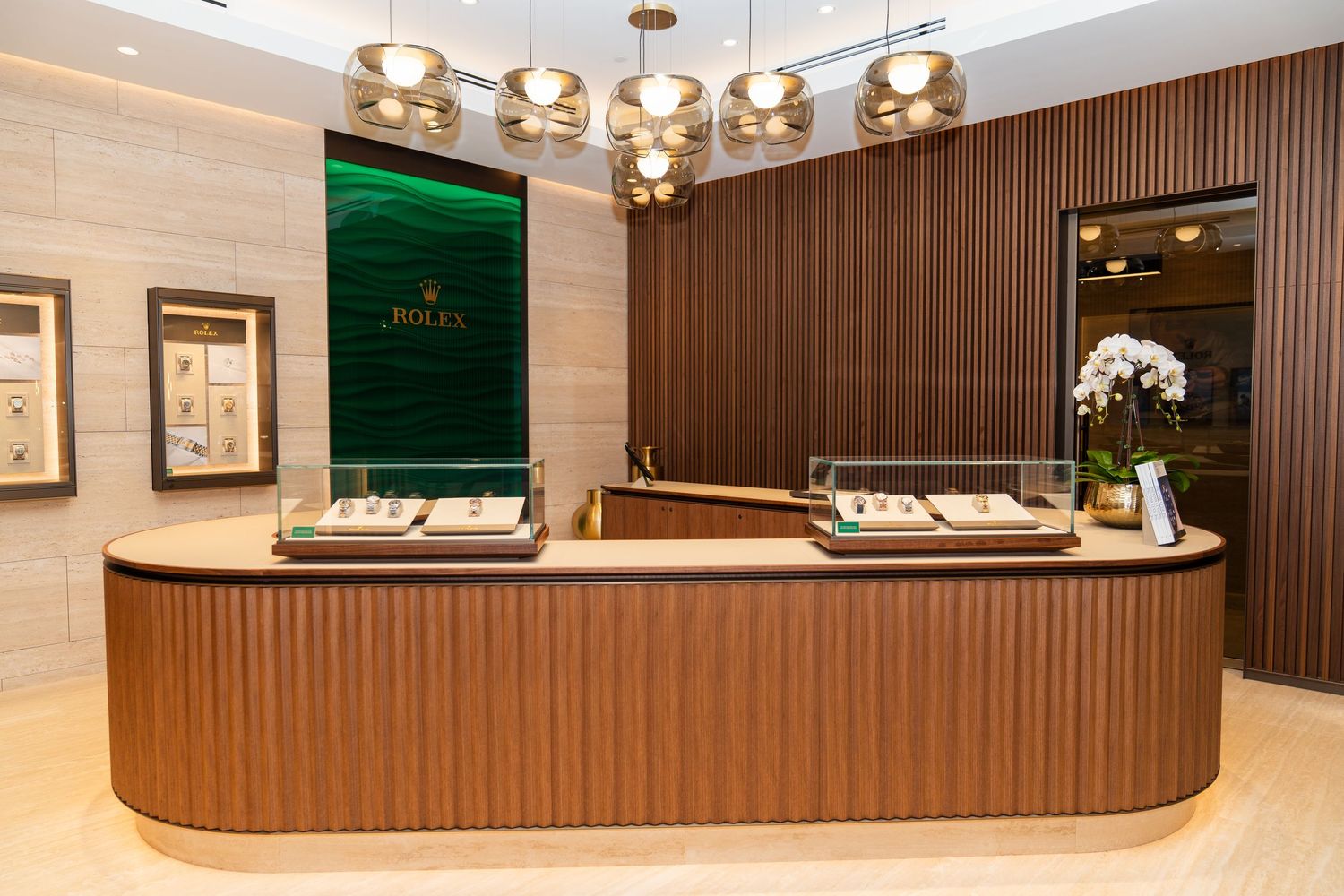 Modern restaurant interior with wood paneling, elegant lighting fixtures, and curved architectural details.