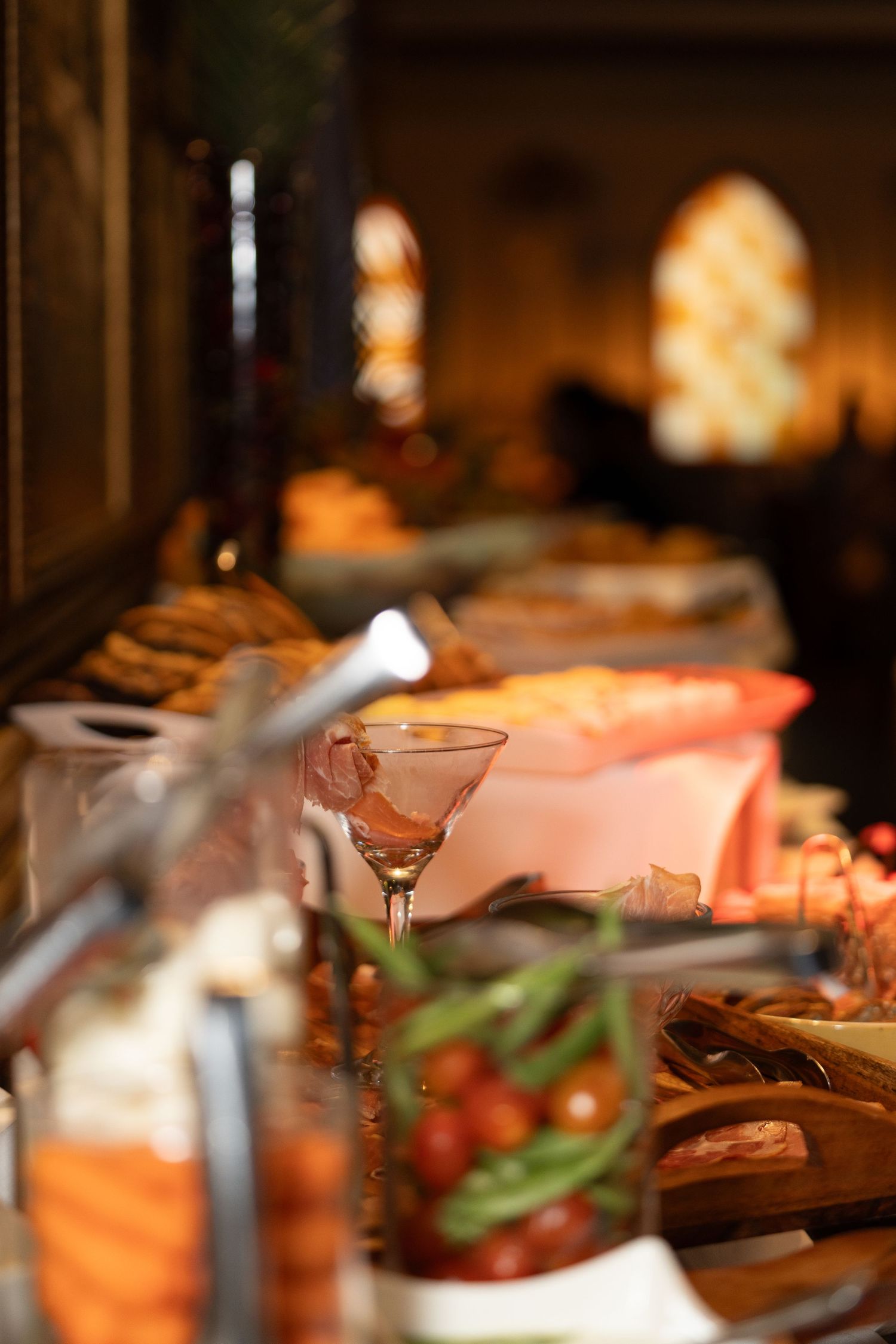 Atmospheric dining table with soft focus on glasses and appetizers in warm lighting.