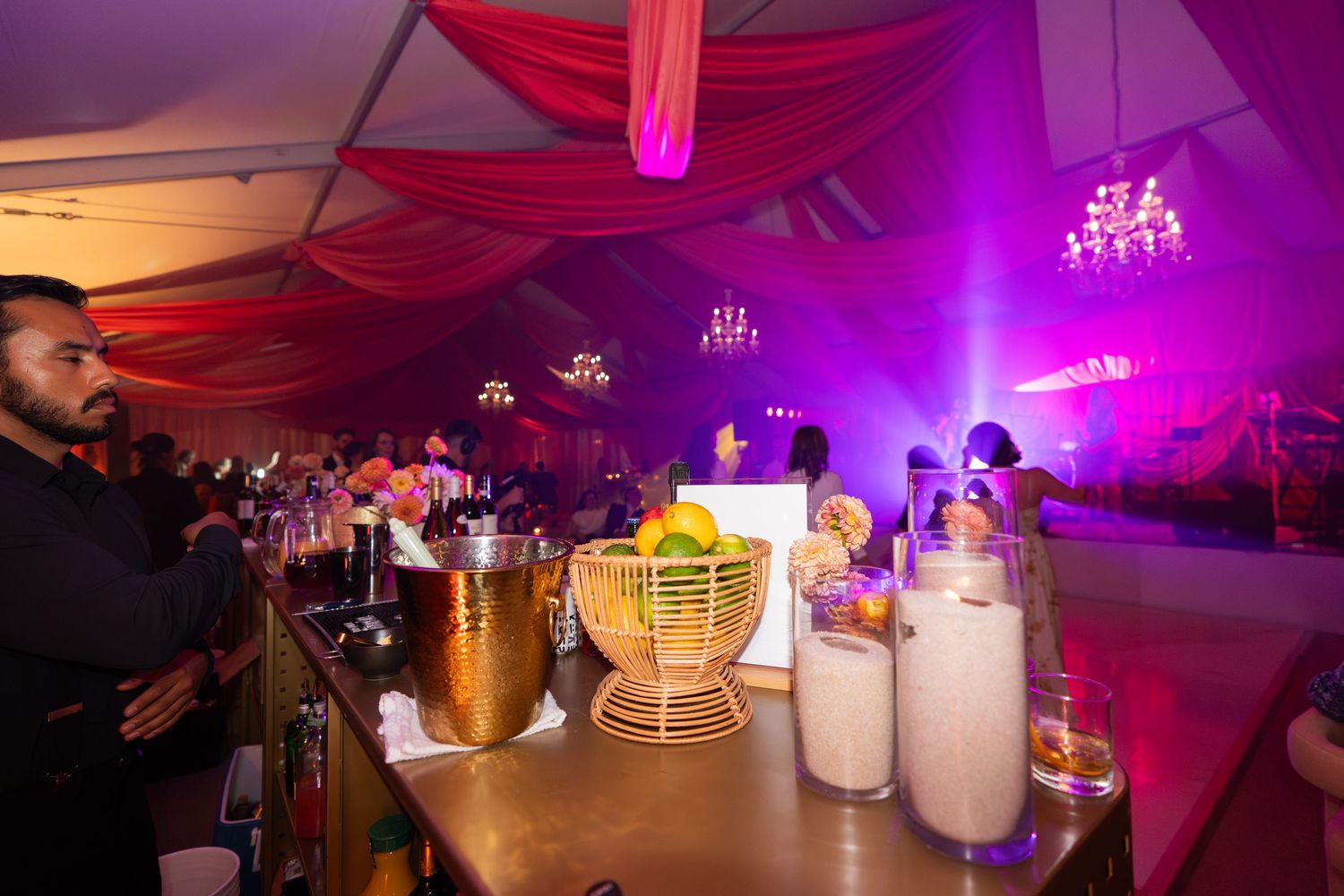 A dimly lit nightclub or bar interior with purple and pink lighting creating a moody ambiance.