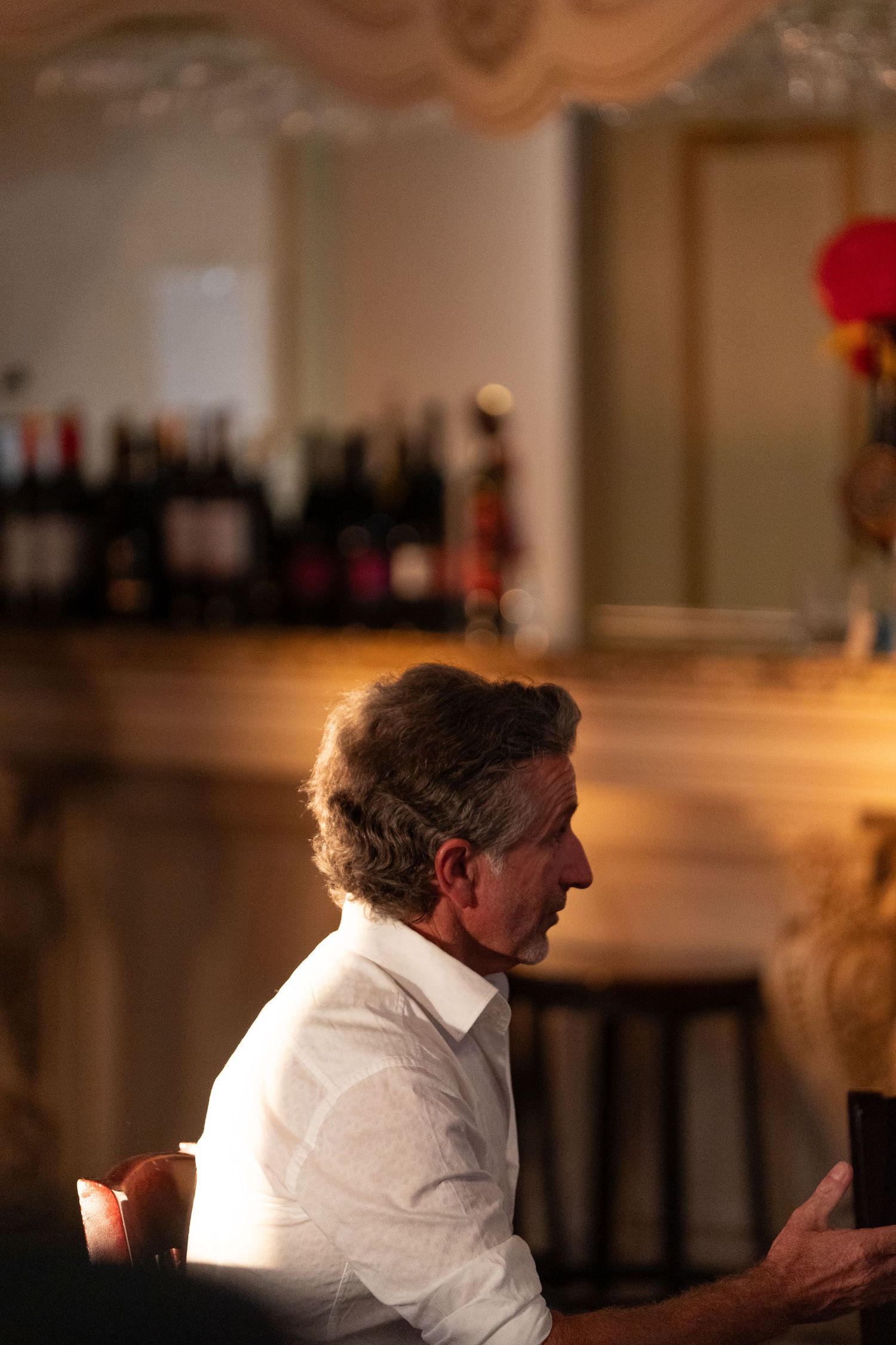 A dimly lit restaurant scene showing a person in white shirt seated at a table.