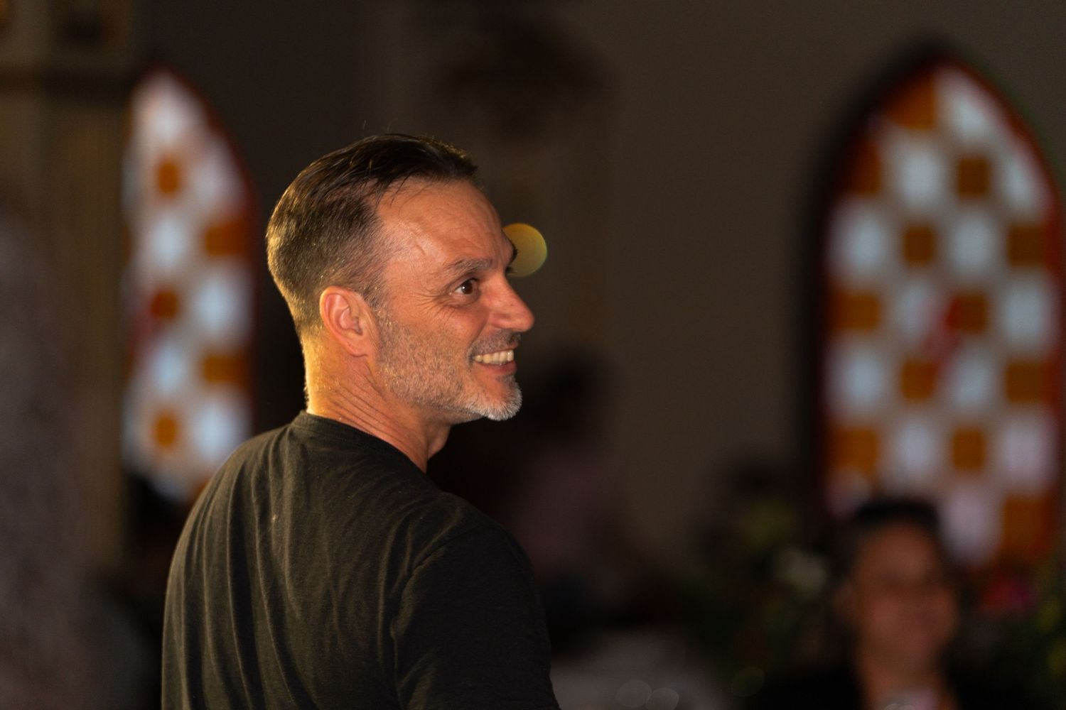 Profile view of person at indoor event with orange checkered decor in background.