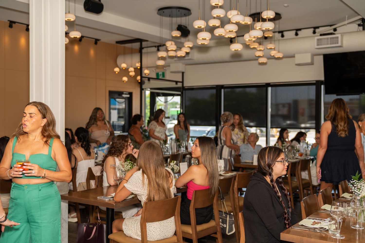Modern restaurant interior with pendant lighting and guests dining in a social atmosphere.