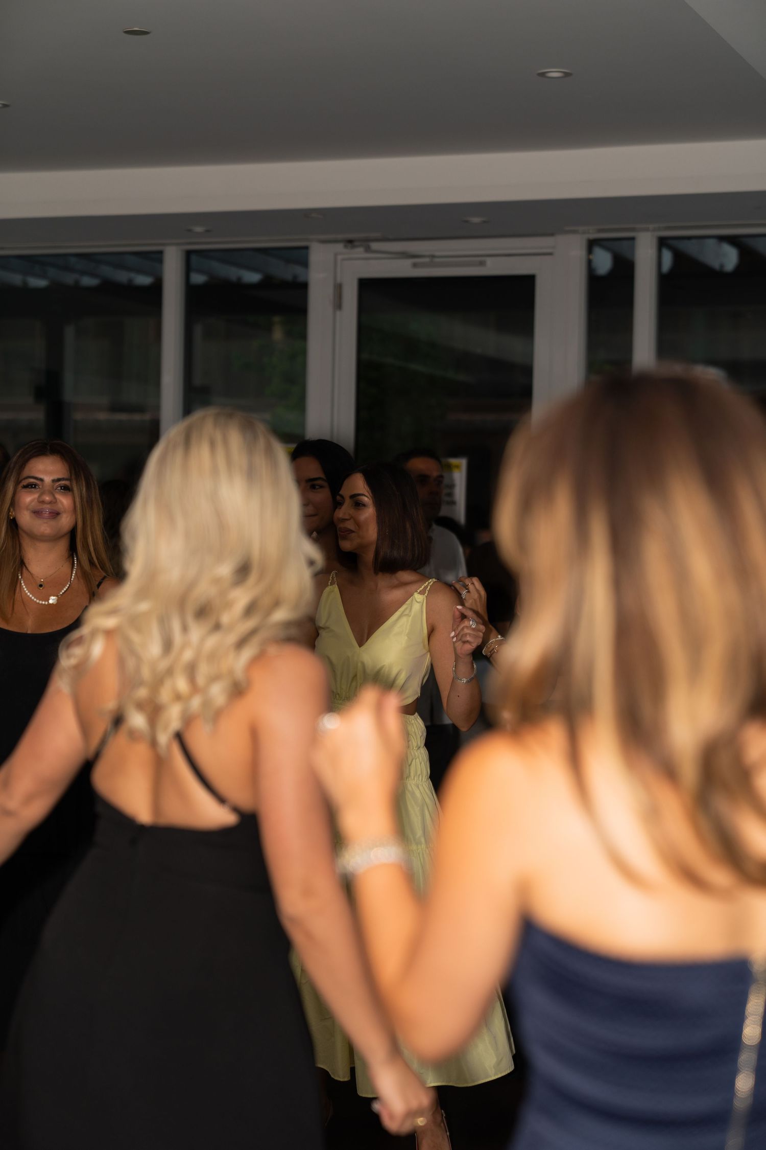 A group of people dancing and having fun at a party in dimly lit indoor venue.