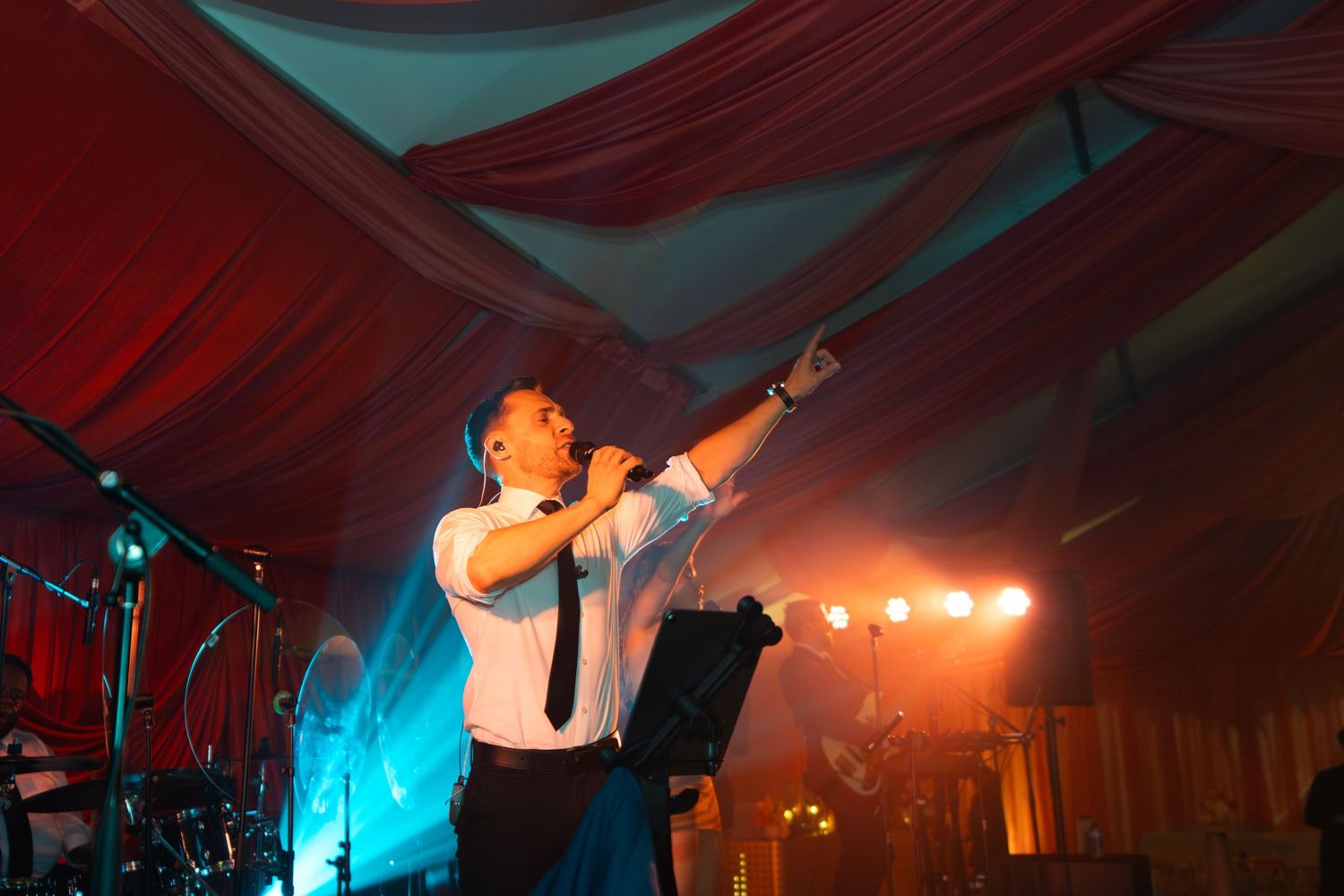 Concert performer silhouetted against dramatic orange and blue stage lighting during an energetic live music performance.