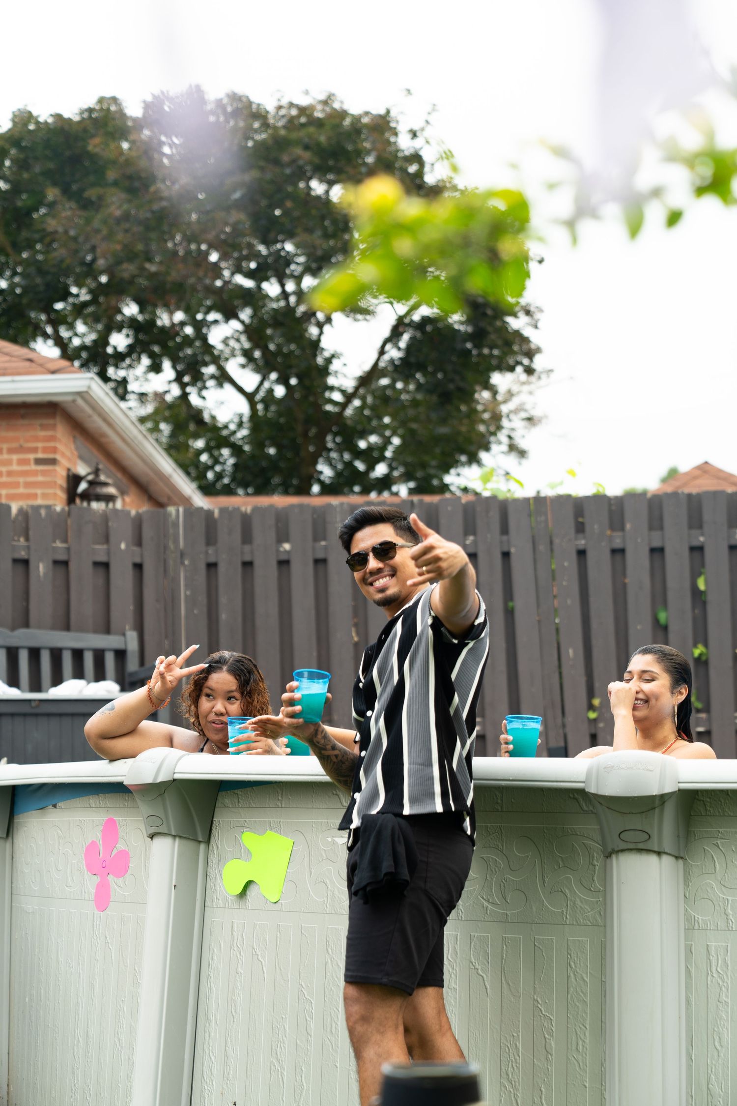 People posing and having fun behind a white fence with colorful drinks.