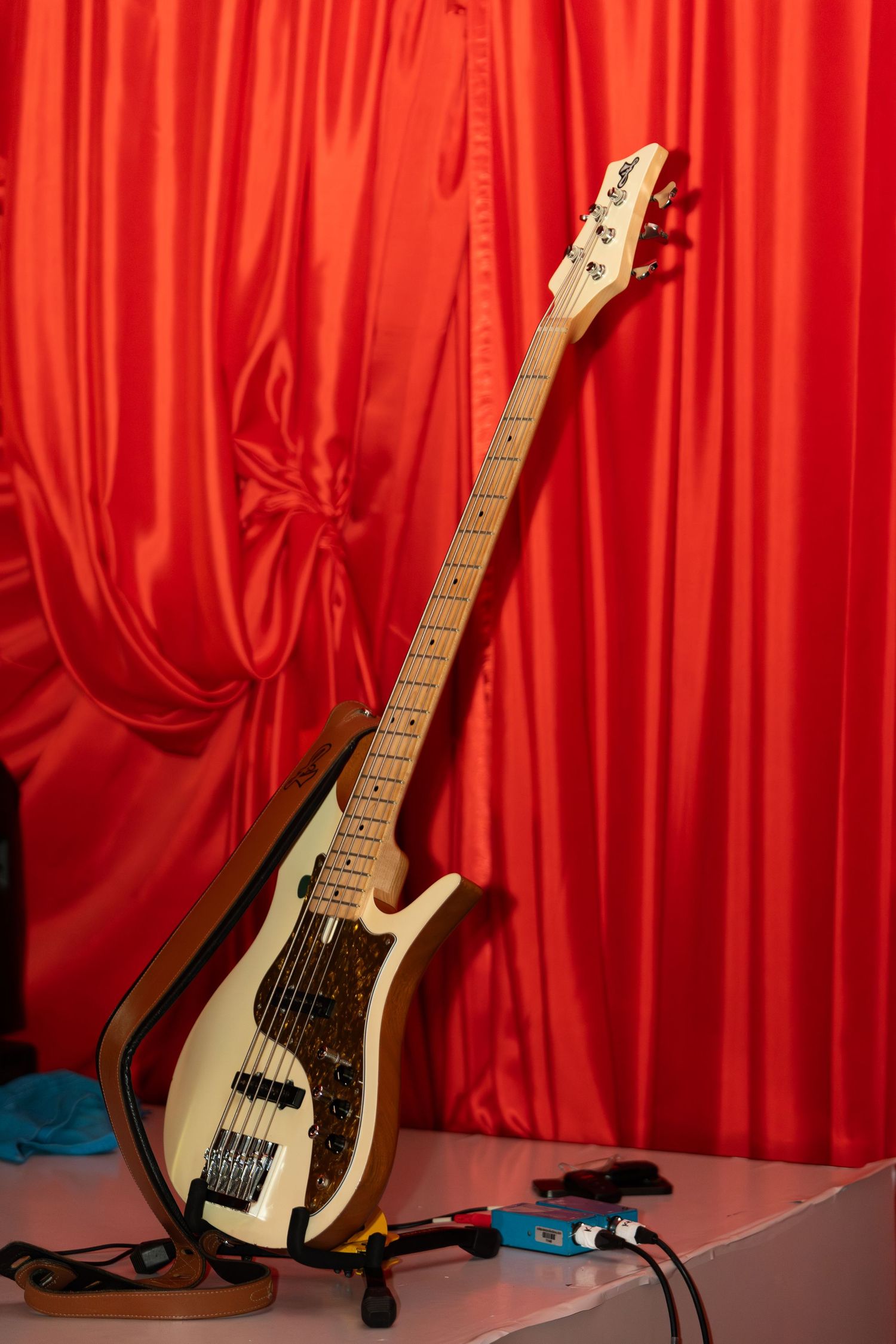 A bass guitar stands against a dramatic red curtain backdrop in a series of four sequential images.