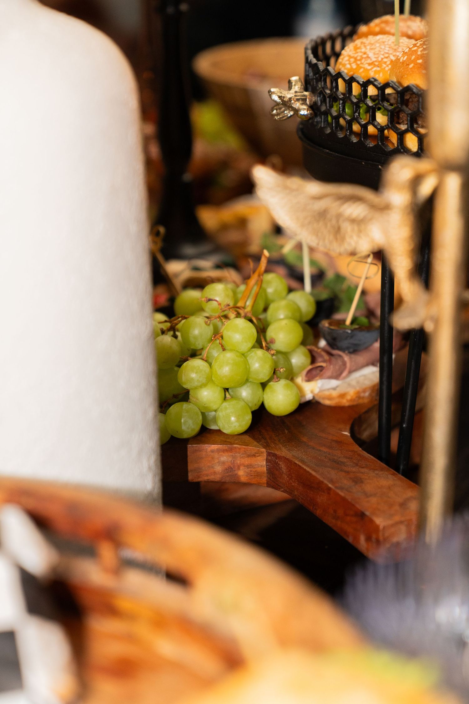 Fresh green grapes displayed on a rustic wooden serving board at a catered event or restaurant setting.