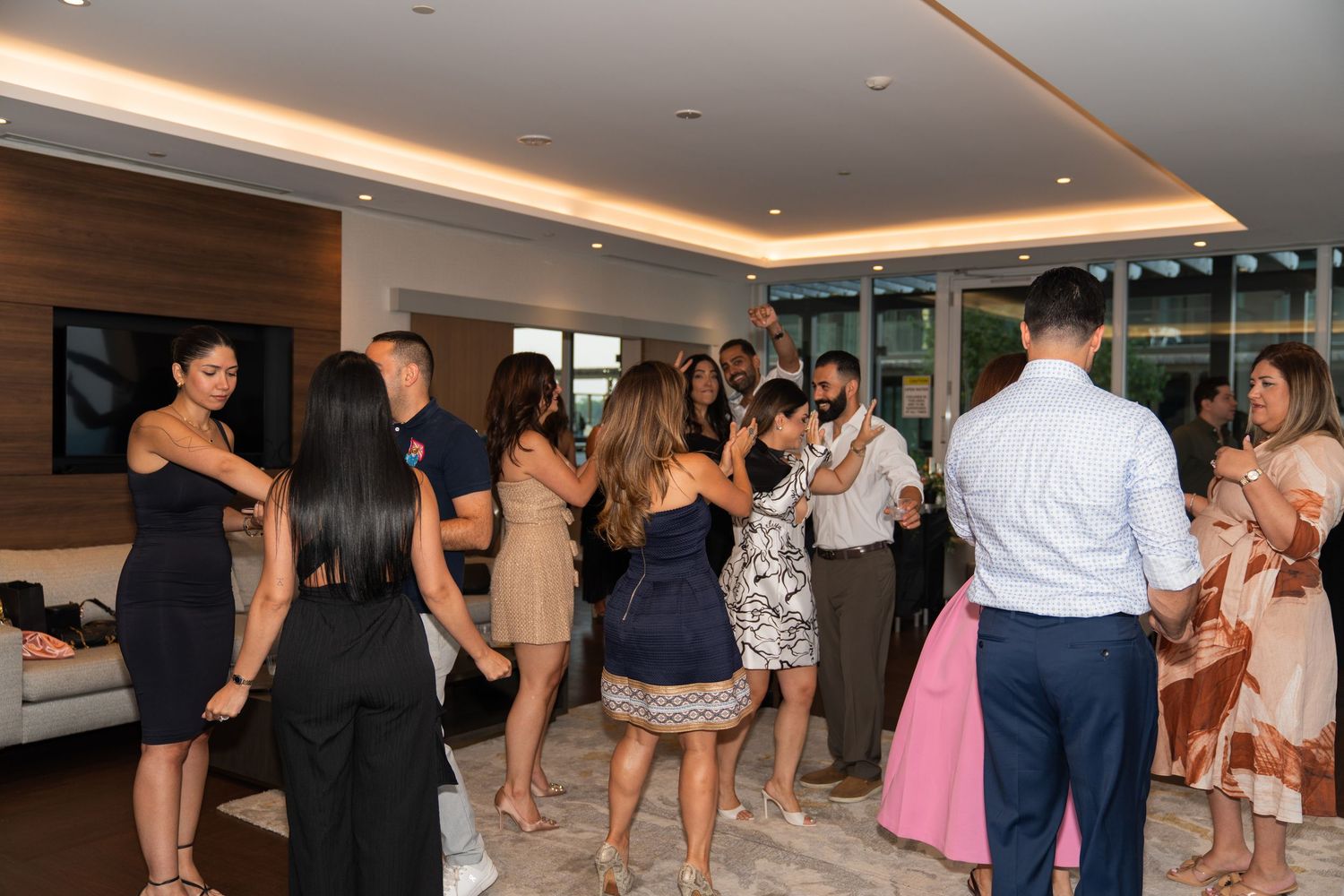 Party guests dance and celebrate at an indoor event with modern lighting and decor.