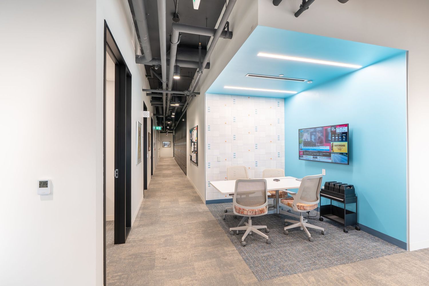 Modern office hallway with blue accent wall features sleek lighting and minimalist design elements.