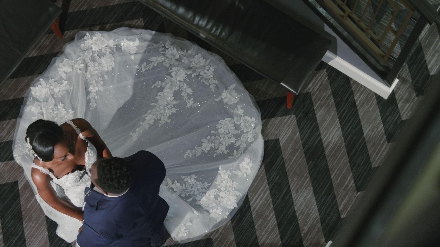 Aerial view of bride and groom embracing beneath stunning circular white wedding veil.