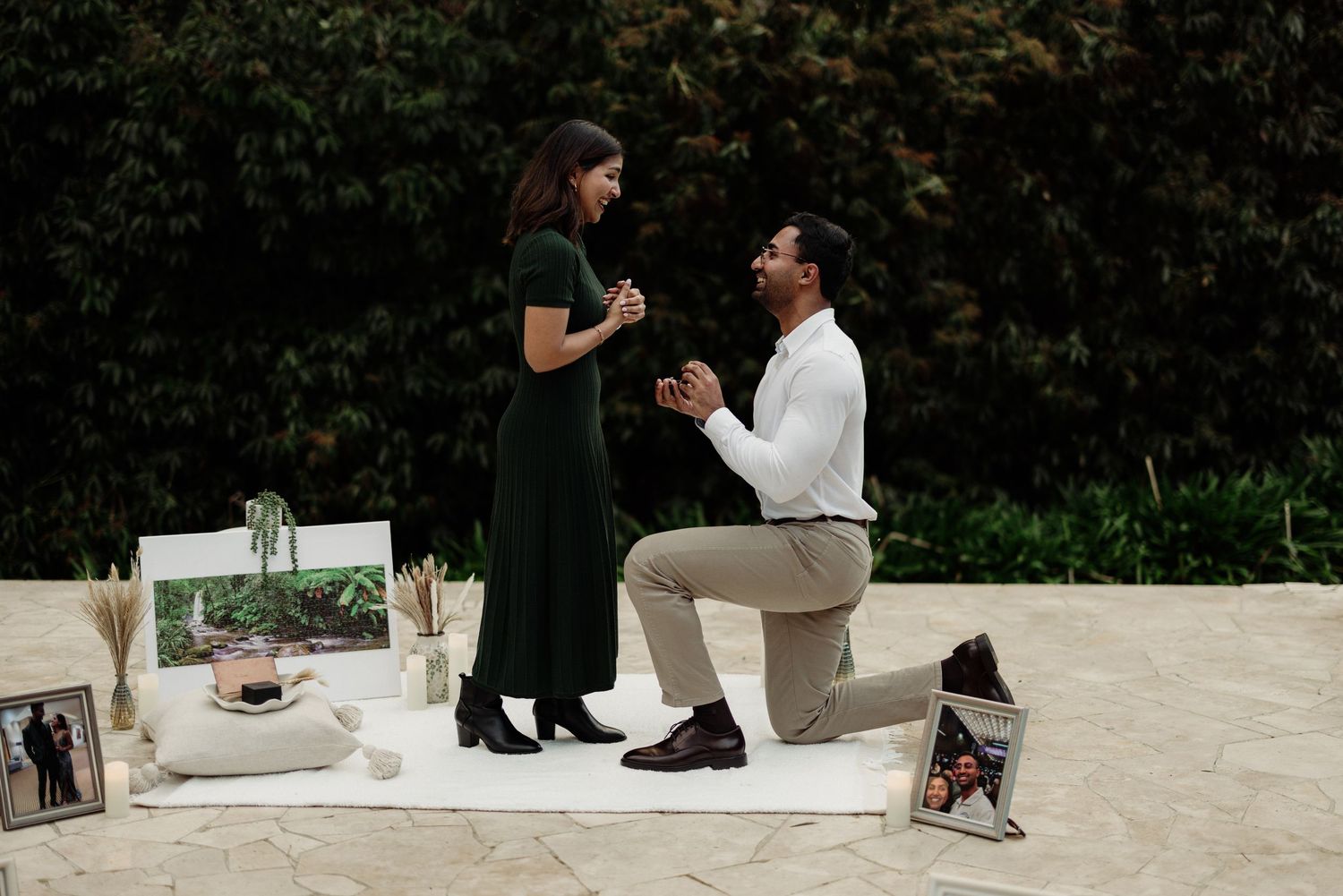 Two people sit on a white outdoor bench in a romantic setting.