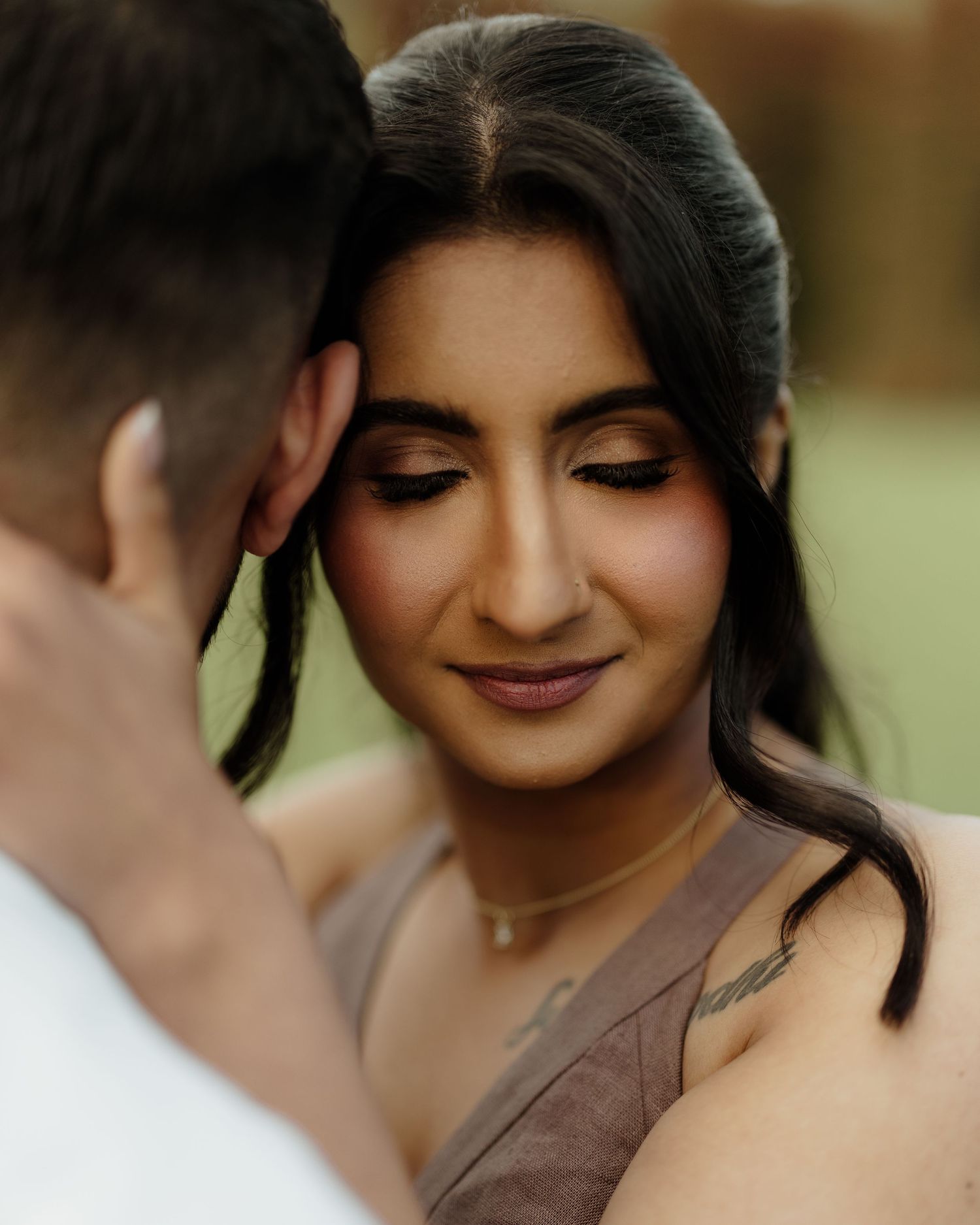 A woman with elegant makeup and dark hair leans close to a man during a romantic couples portrait session.