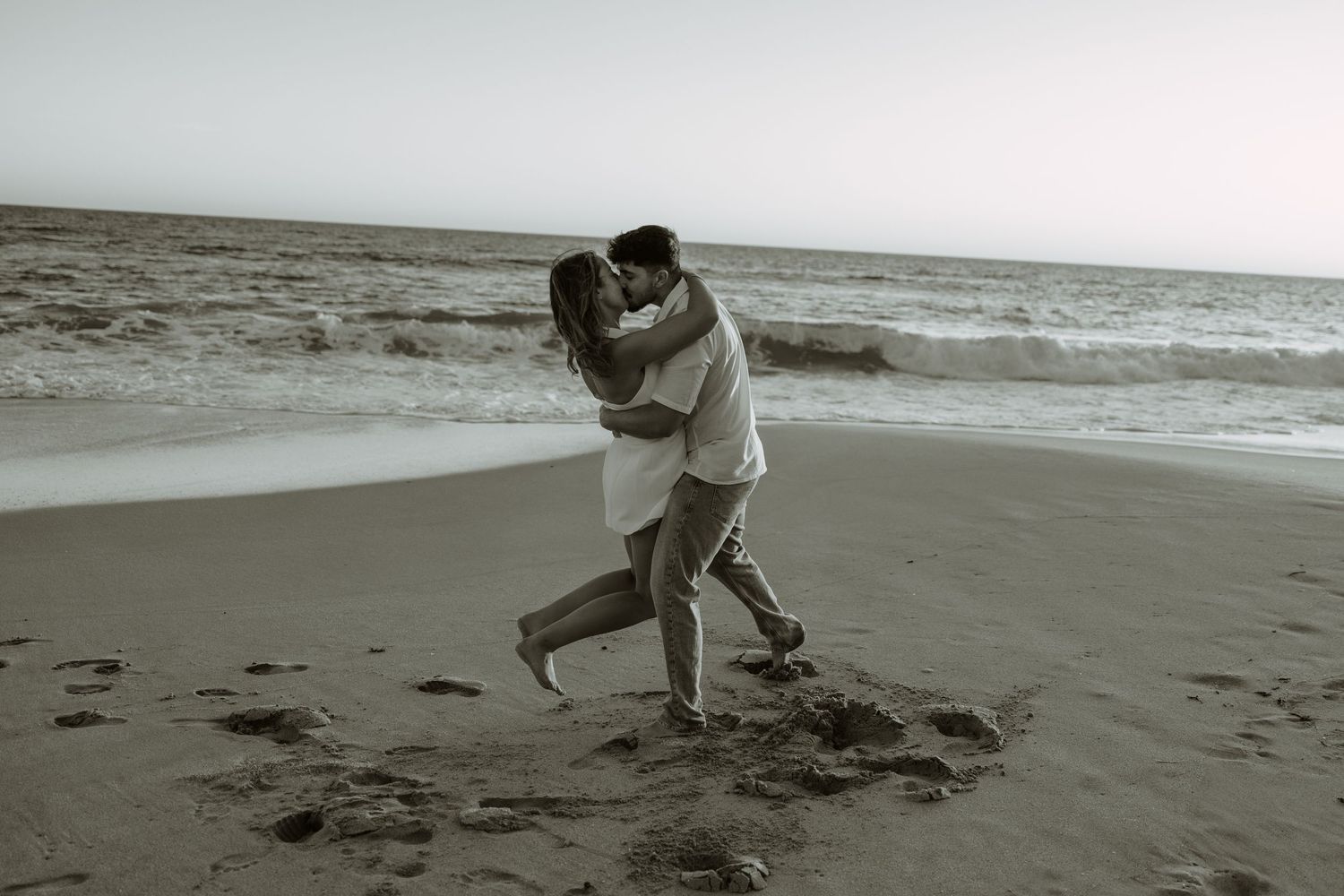 Dancing couple dips dramatically on a beach during a romantic photoshoot.