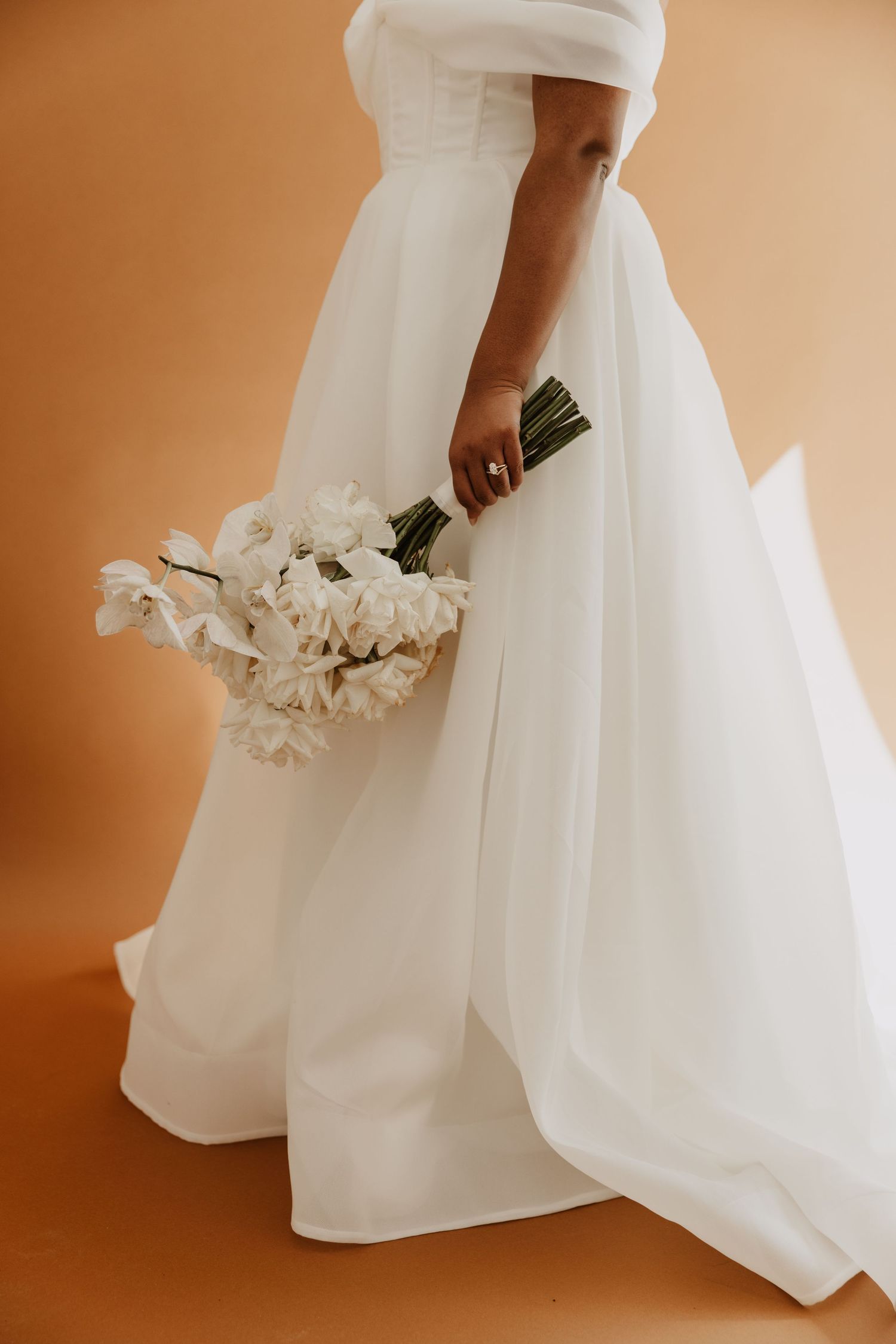 Close-up details of a flowing white wedding dress with delicate fabric and floral accents.
