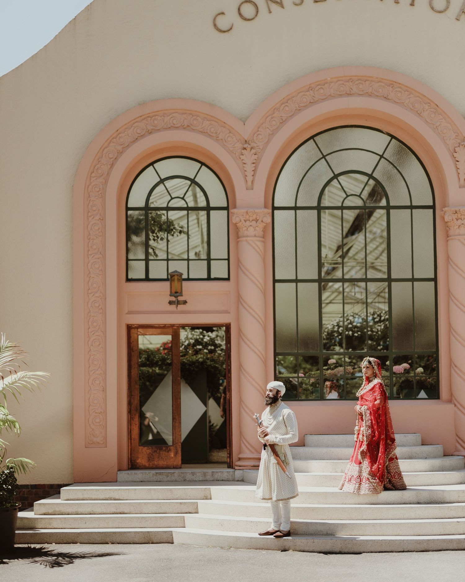 A series of five connected photos showing a romantic couple in elegant attire posing against a pink building with arched windows.