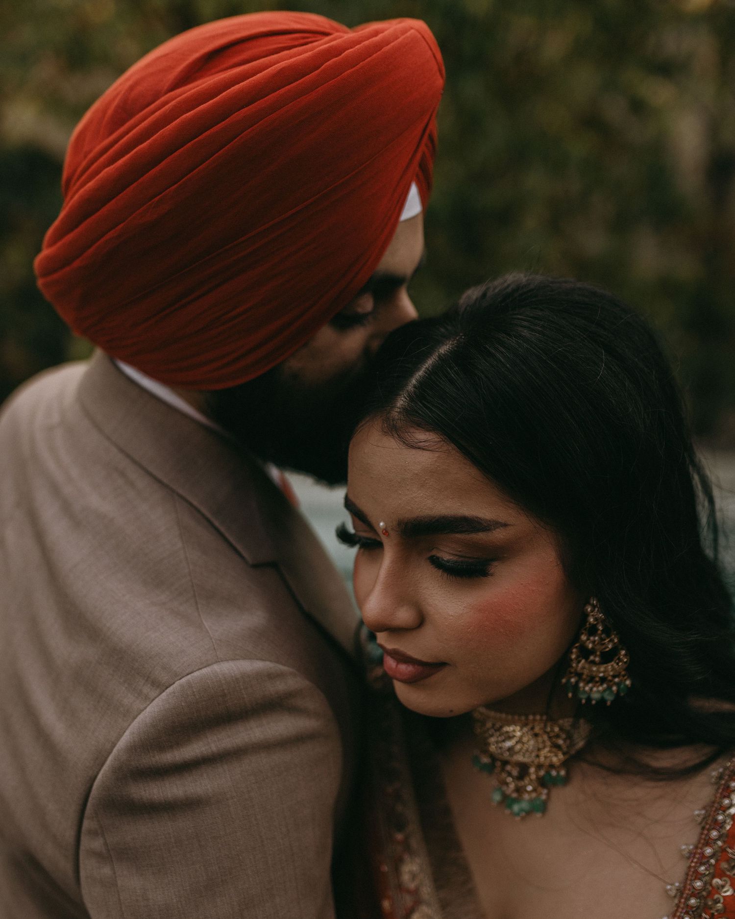 Intimate couple portrait showing traditional Sikh turban and elegant bridal makeup in warm lighting.
