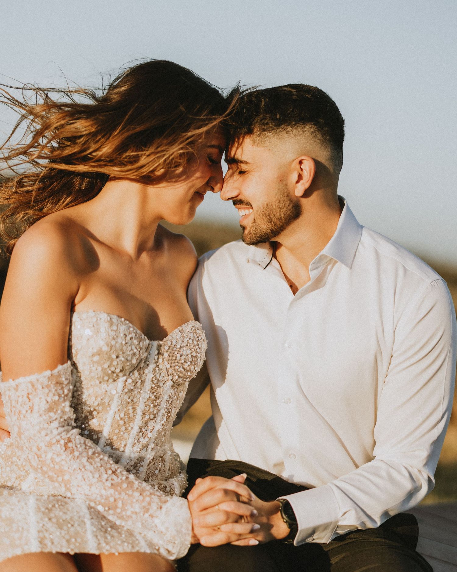 A romantic couple in wedding attire embraces against a sunset backdrop in a series of intimate portrait photos.