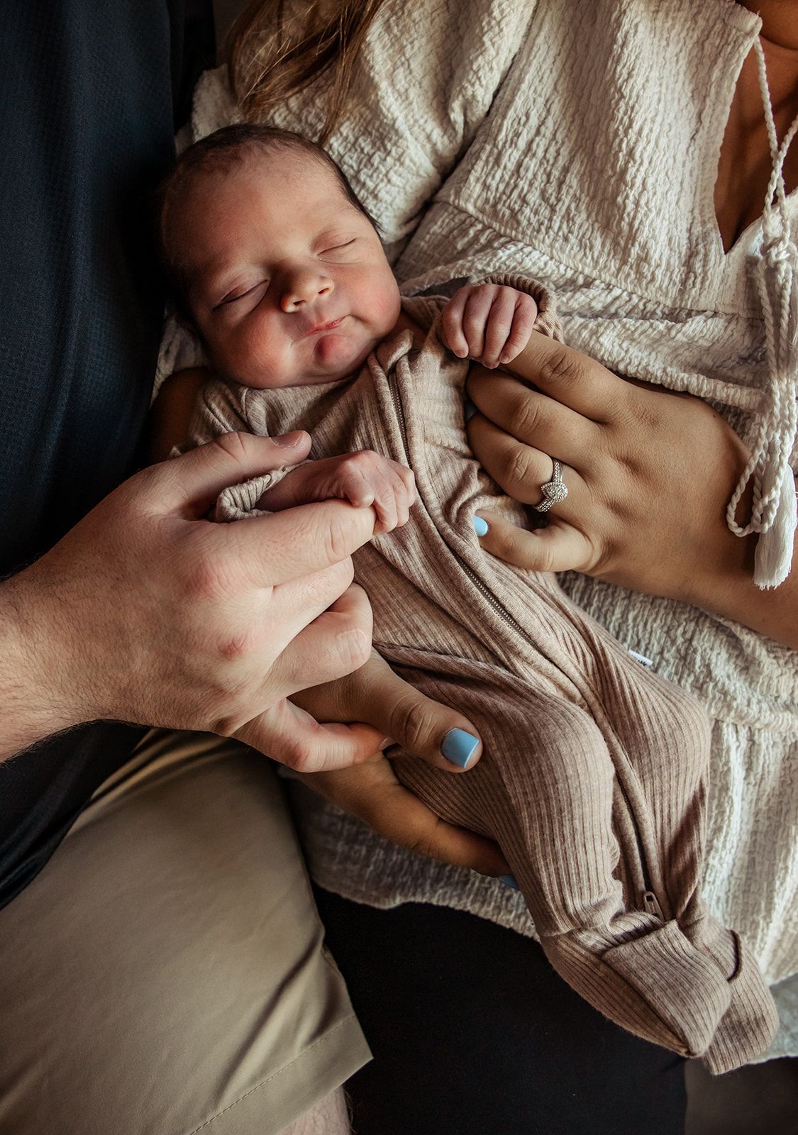Peaceful sleeping newborn in beige outfit held by caring hands. fresh 48