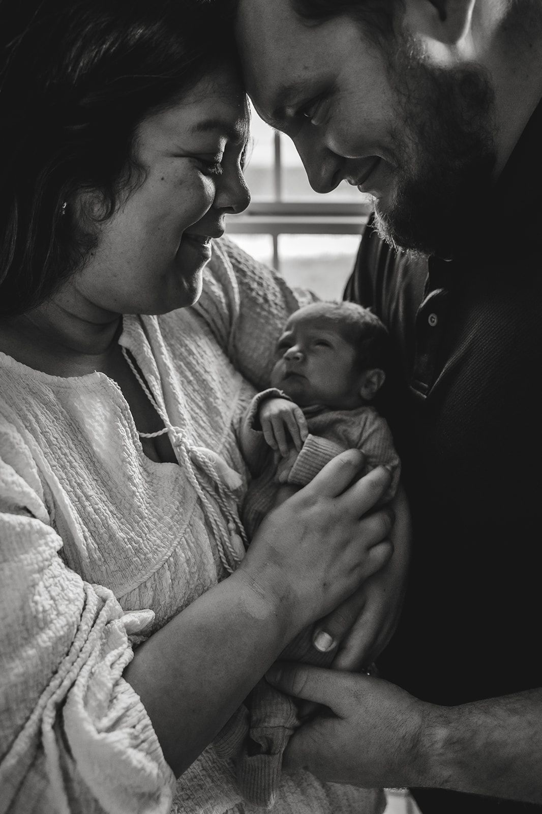 Intimate black and white portrait of new parents with their sleeping newborn. fresh 48