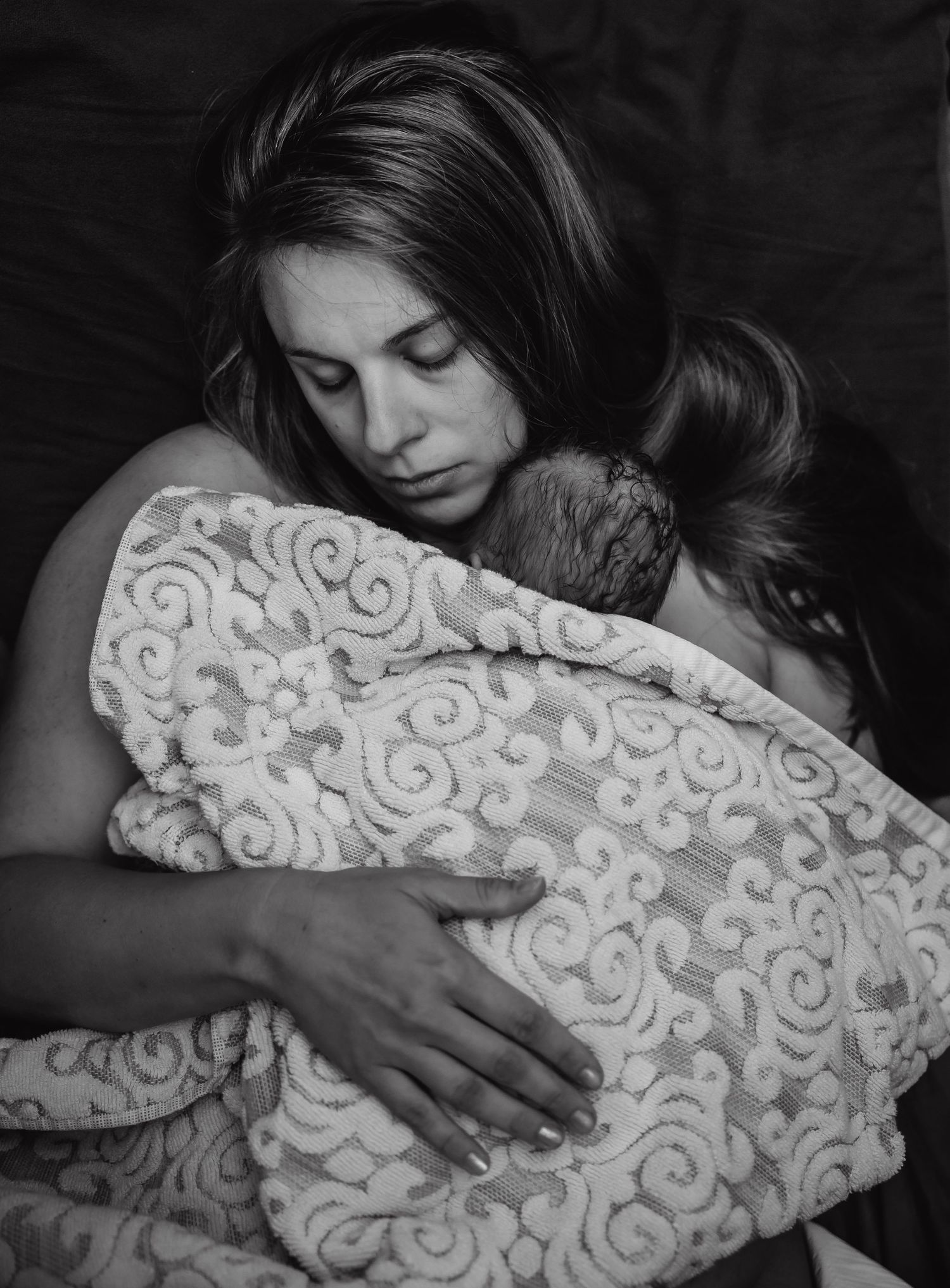 Third time mom snuggling her newborn baby after a home birth