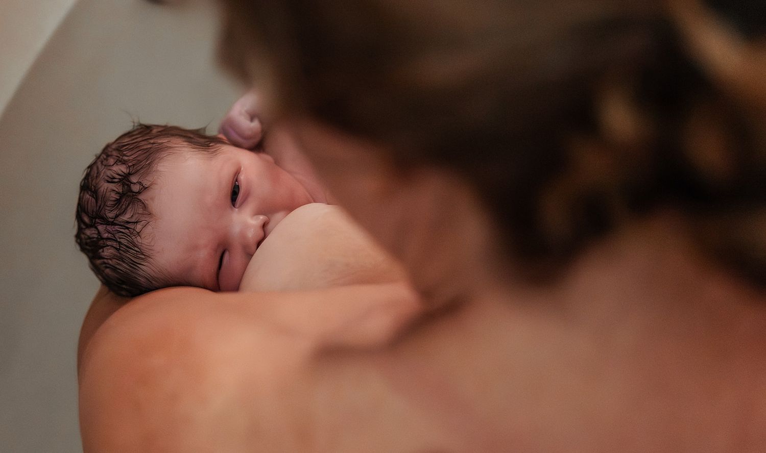 Minutes old newborn breastfeeding in tub at The Birth Center of Midland