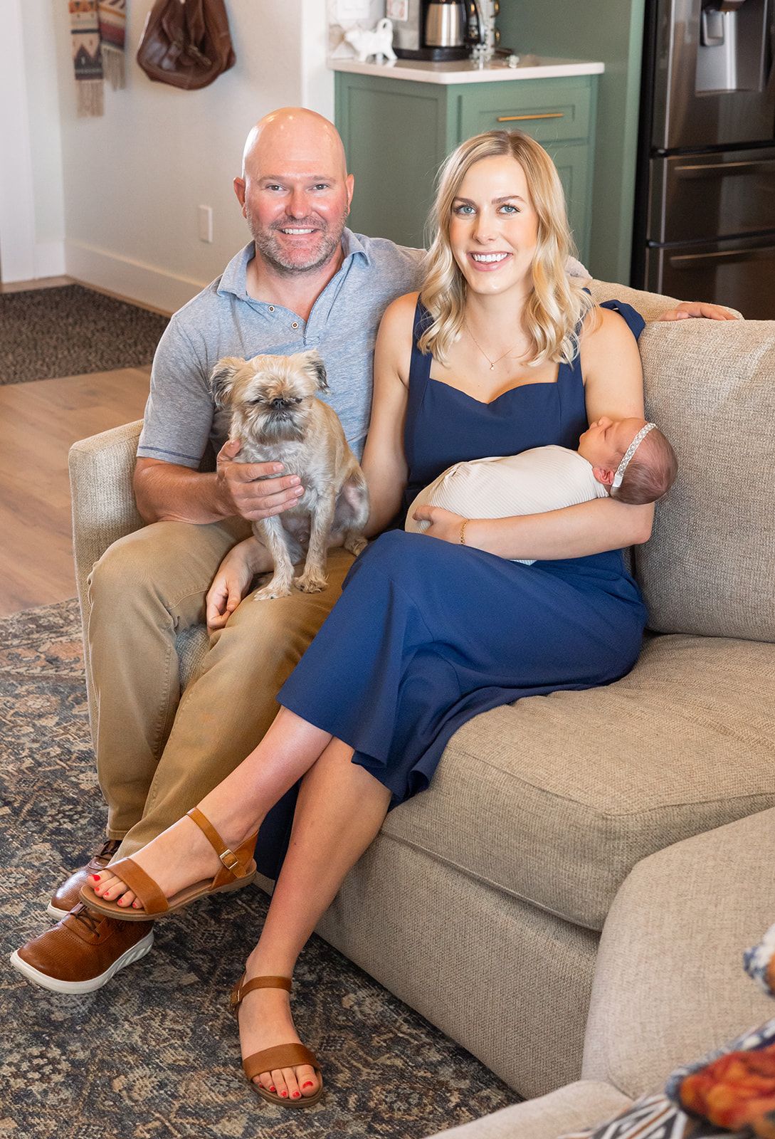 A family sitting on a couch smiling for a photo during a Fresh 48 session in their home