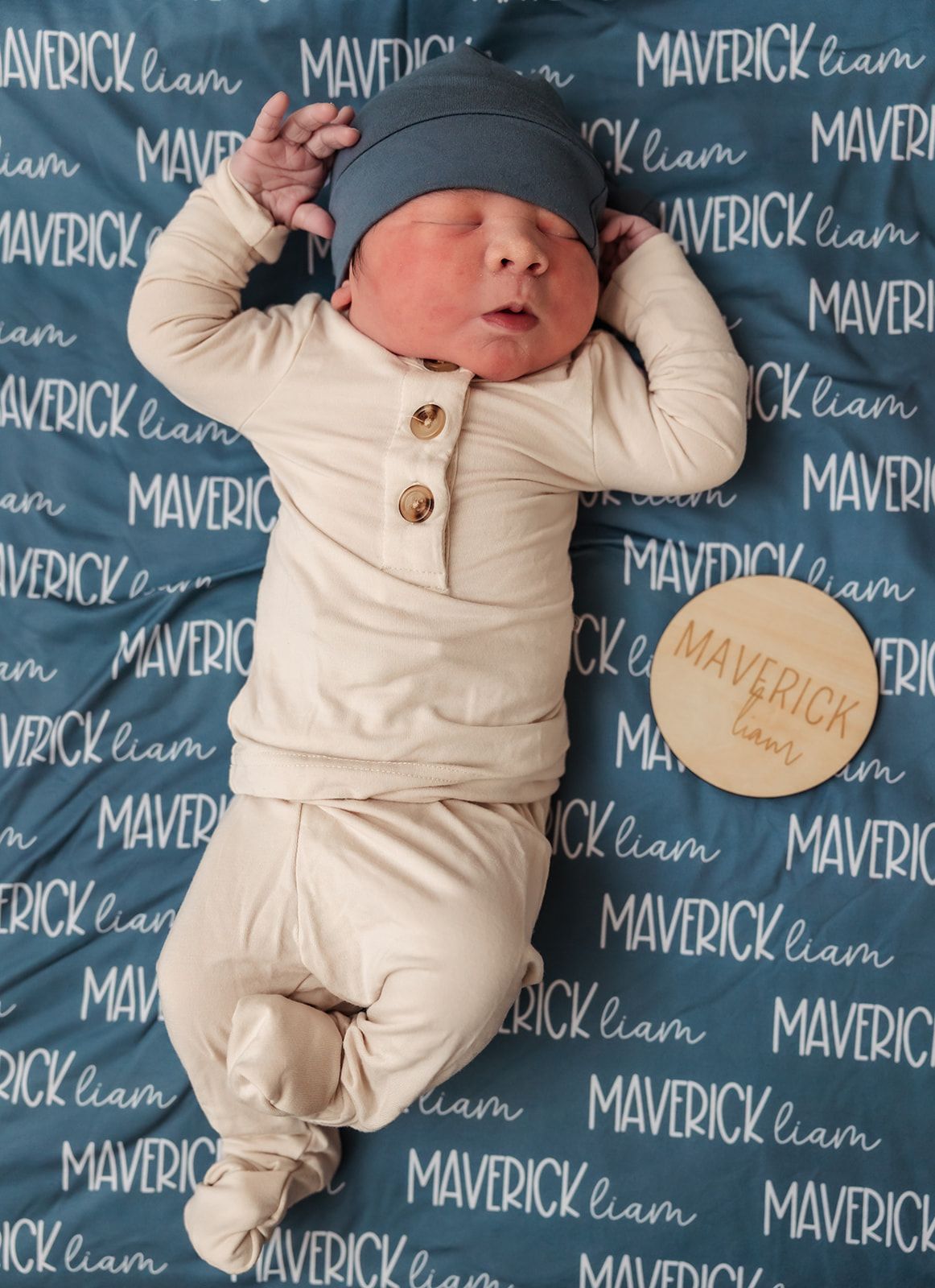 Sleeping newborn in cream outfit against blue Maverick-patterned backdrop. fresh 48 session