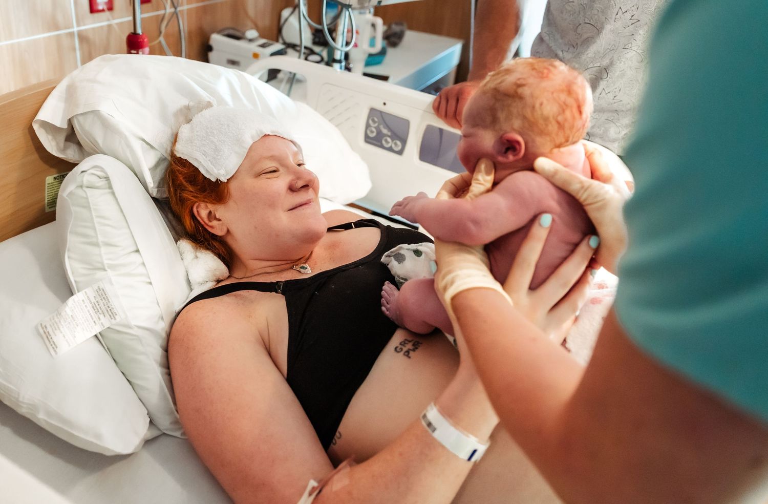 Proud new mom smiles at her newborn baby at Midland Memorial Hospital in the delivery room after birth.