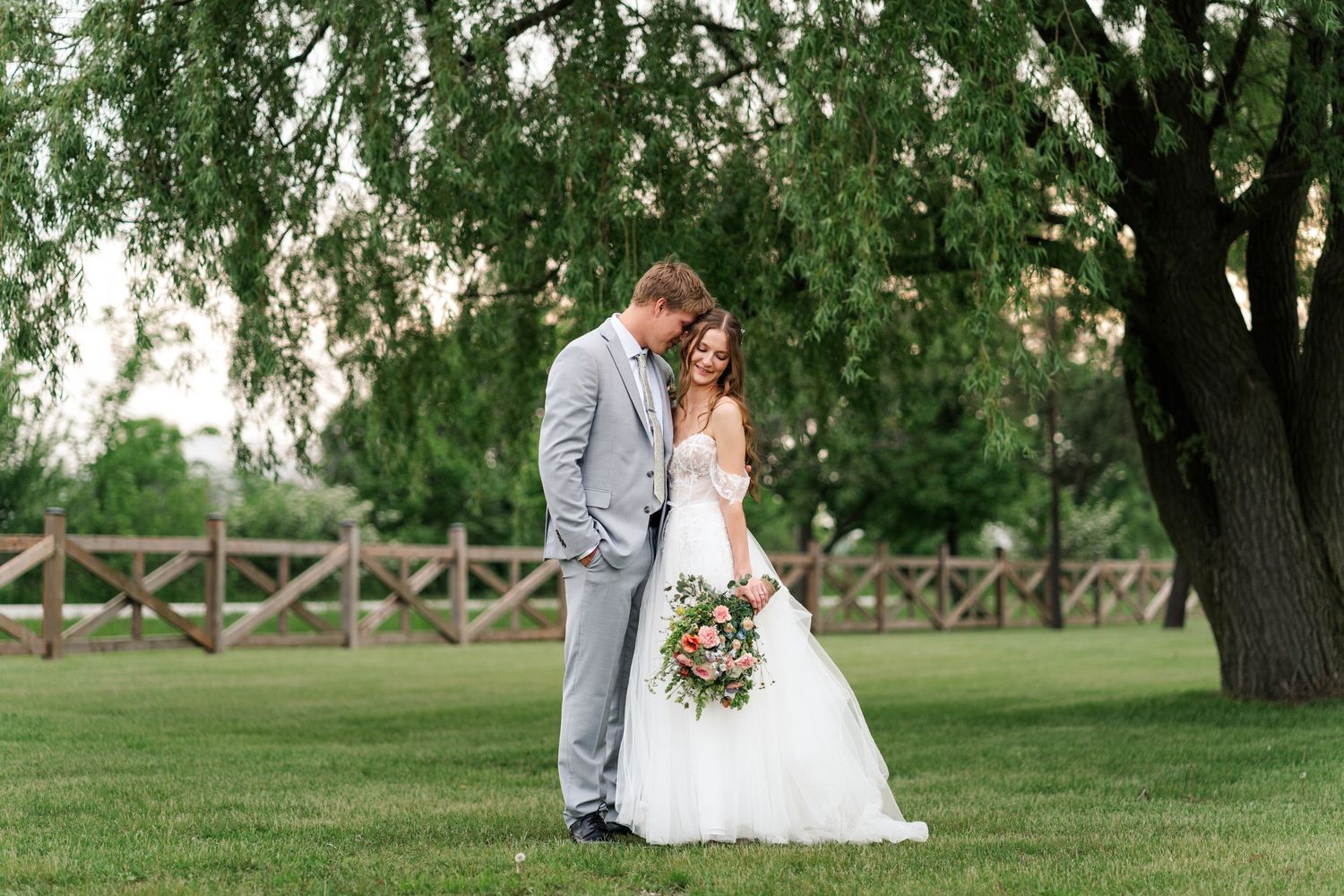 Bride and groom share intimate moment on manicured lawn under weeping willow tree.
Niagara wedding photos.