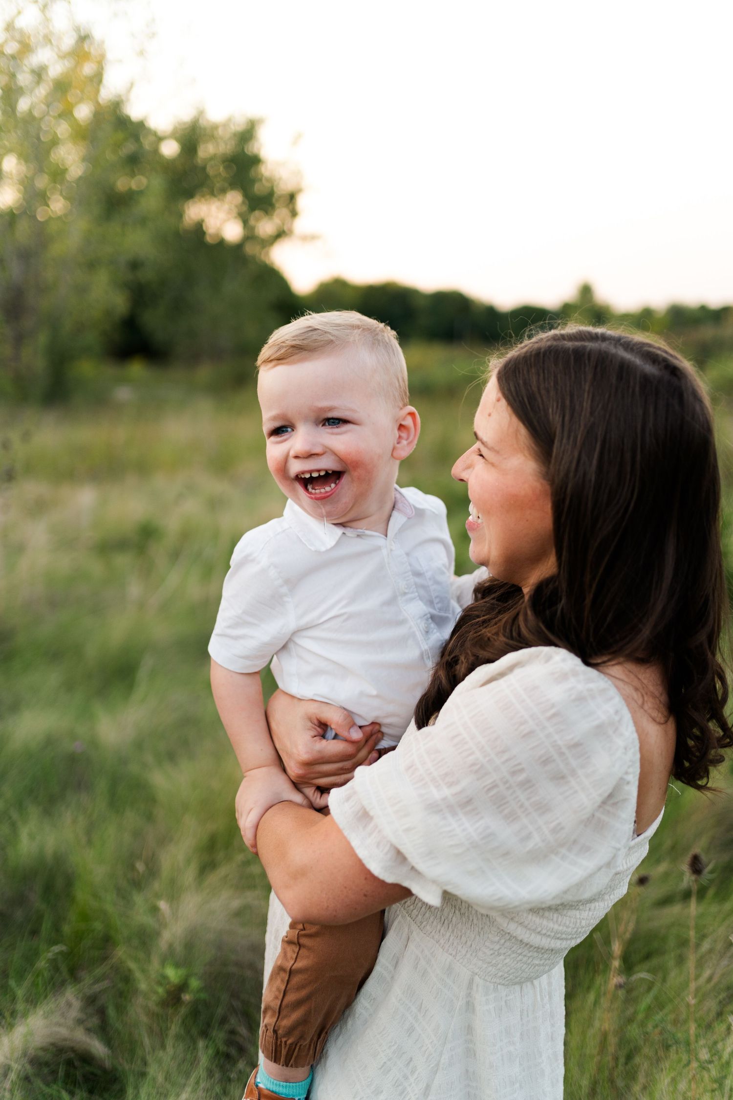 A joyful outdoor portrait of a mother and laughing toddler in a natural setting at sunset.
Family photos in Niagara