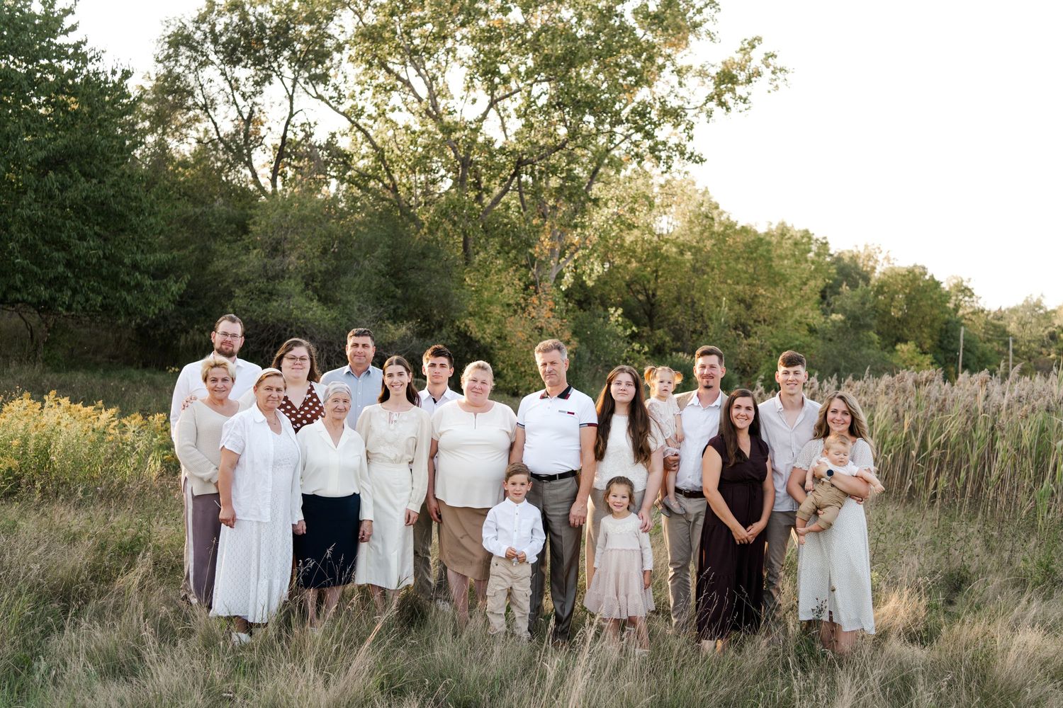 A group poses together outdoors wearing coordinated white and neutral colored outfits.
Niagara family photos.
